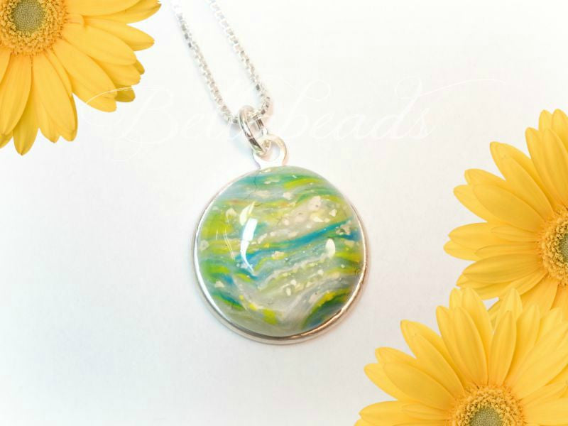 Sterling silver round pendant with a white, yellow, and green swirled  clay swirled with flowers.
