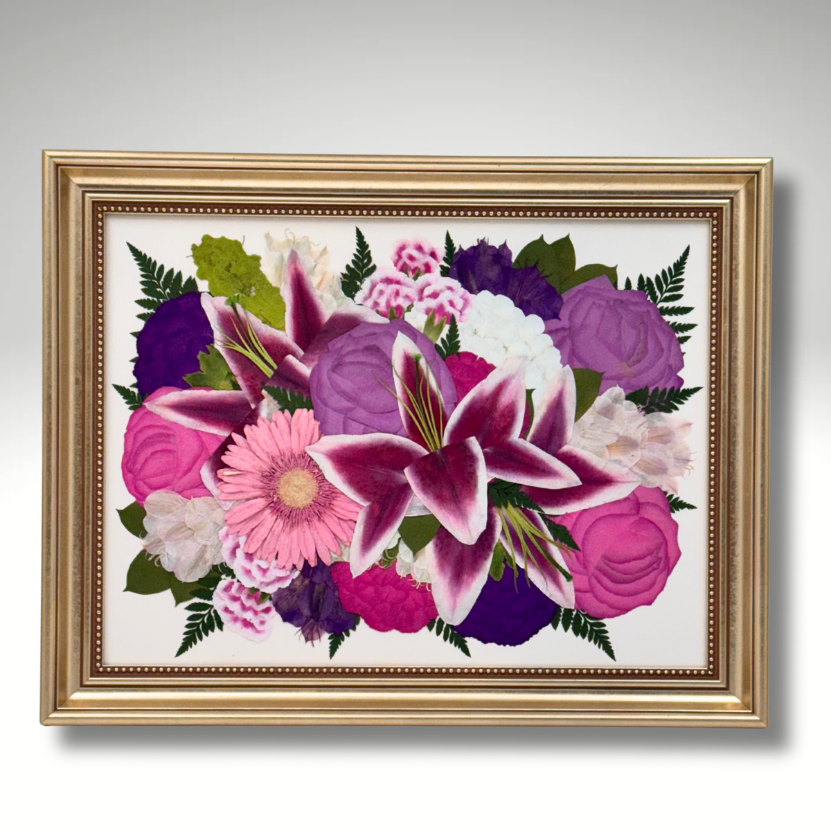 Framed 12x16 custom pressed flower arrangement featuring vibrant pink lilies, purple roses, and a mix of preserved wedding or memorial blooms in a gold frame.