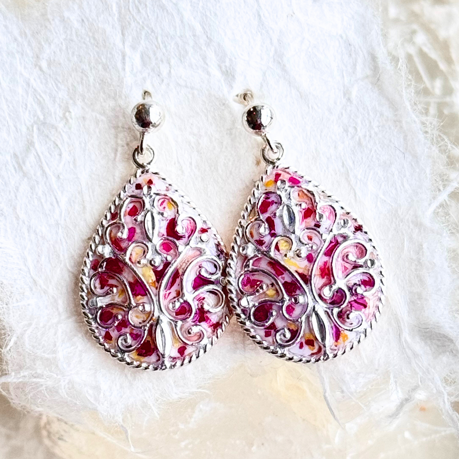 Close-up of Floral Keepsake Earrings showing intricate scrollwork details and preserved flower inlay in a sterling silver teardrop frame.