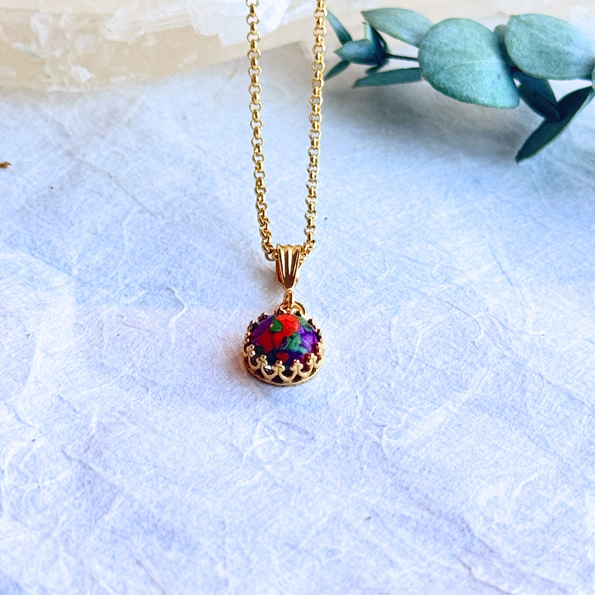 Side view of the Crown of Memories Pendant showcasing the preserved flowers within the gold-plated crown design.