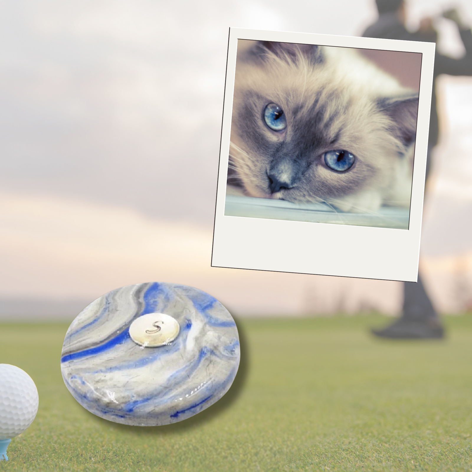 Personalized golf ball marker made with pet ashes or fur in a swirl of blue, white, and gray resin. Displayed on a golf course with a photo of a Siamese cat, honoring a cherished companion. Unique cremation keepsake for golfers.