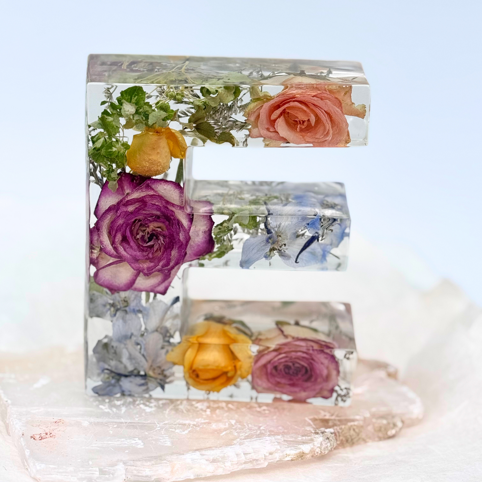 Clear resin letter E with preserved roses and wildflowers from wedding or funeral bouquet