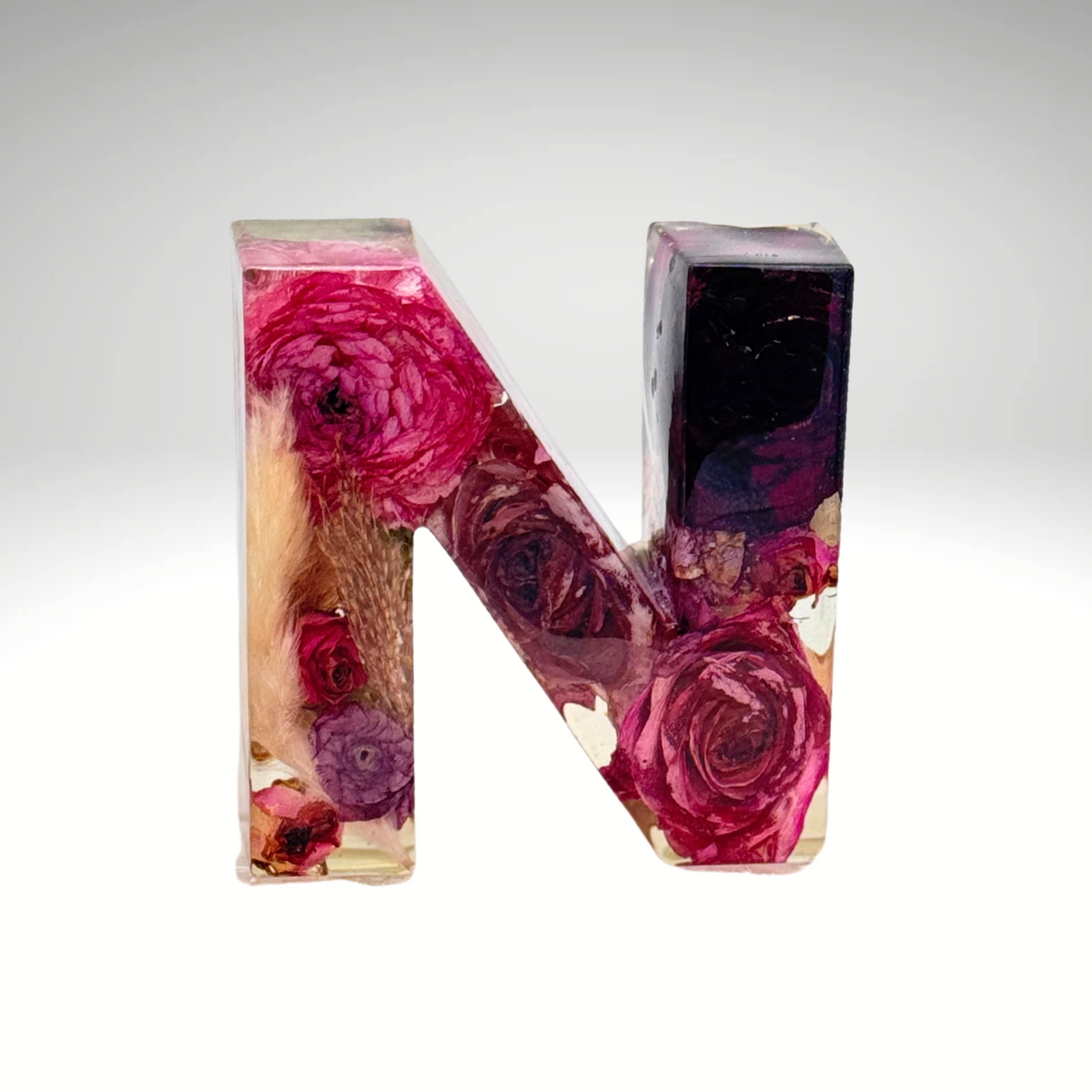 Clear resin letter N with vibrant pink and dark preserved flowers from wedding or memorial bouquet, bold floral keepsake