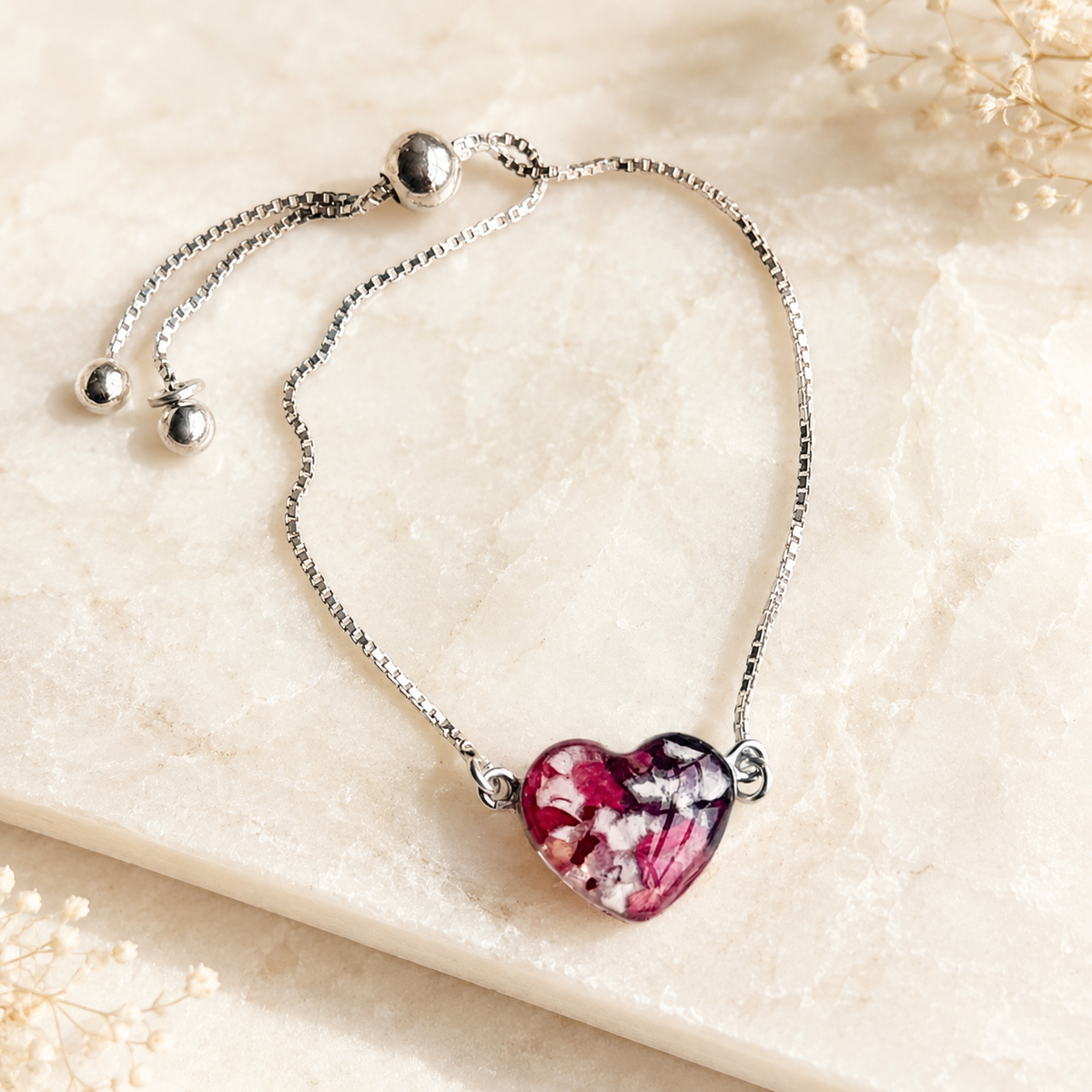 Demi Heart Memorial Bracelet handcrafted in sterling silver with a heart-shaped preserved flower centerpiece and adjustable slider chain. Custom memorial bracelet made with wedding flowers, funeral flowers, ashes, or pet fur.