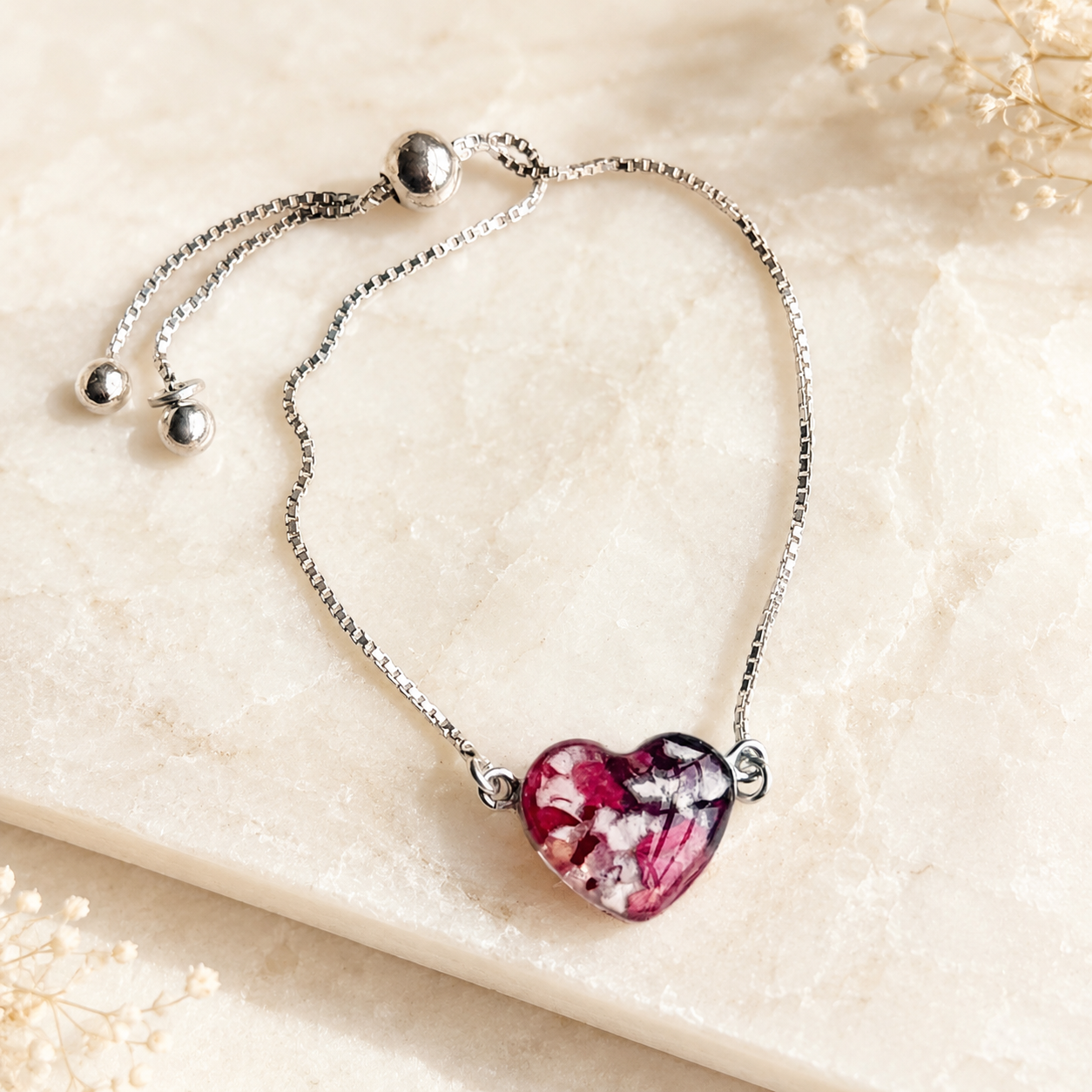 Demi Heart Memorial Bracelet handcrafted in sterling silver with a heart-shaped preserved flower centerpiece and adjustable slider chain. Custom memorial bracelet made with wedding flowers, funeral flowers, ashes, or pet fur.