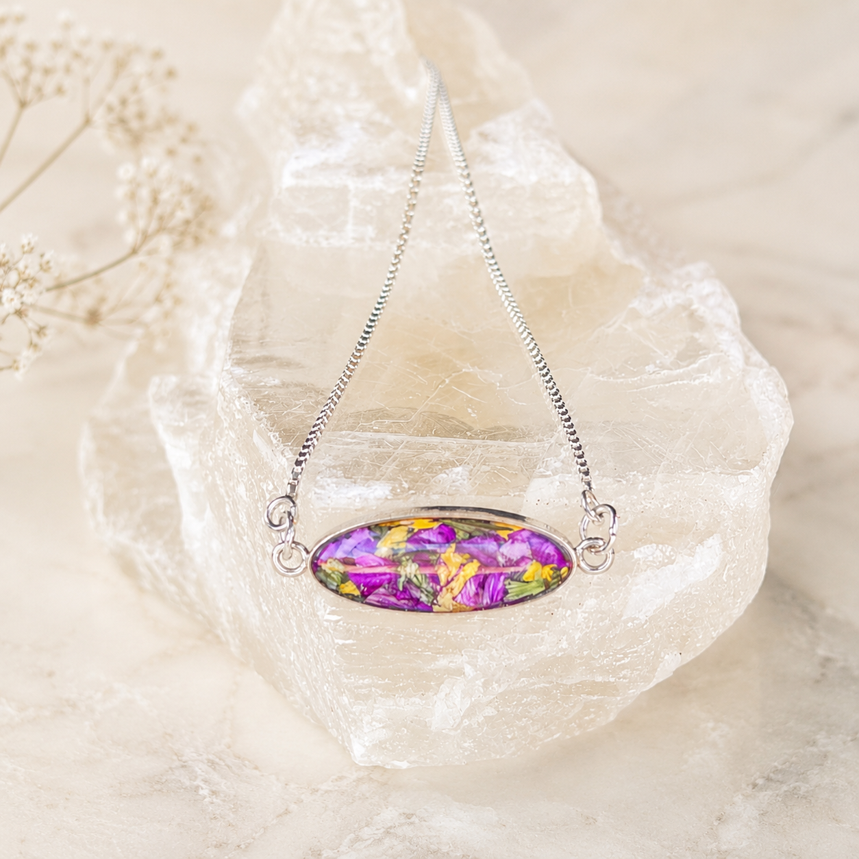 Eternal Grace Memorial Bracelet handcrafted in sterling silver with an oval preserved flower centerpiece and adjustable slider chain. Custom memorial bracelet made with wedding flowers, funeral flowers, ashes, or pet fur.
