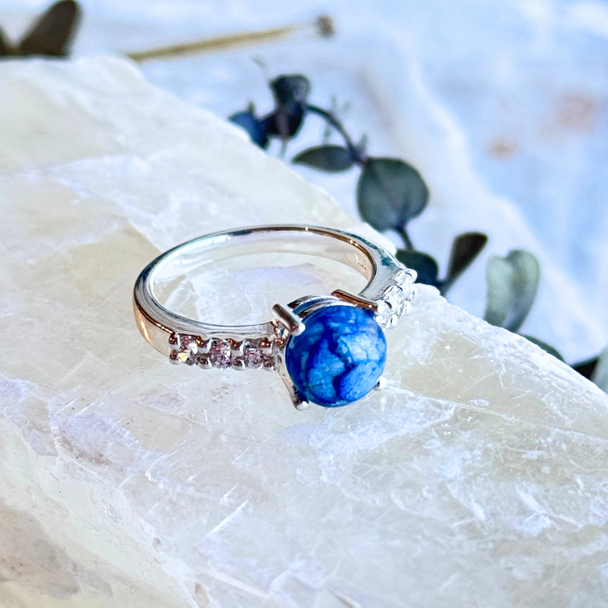 A handcrafted Eternity Bloom Memorial Ring featuring a blue hydrangea-infused stone, symbolizing gratitude and remembrance. Set in a delicate band with accent stones, this memorial jewelry piece preserves cherished moments.