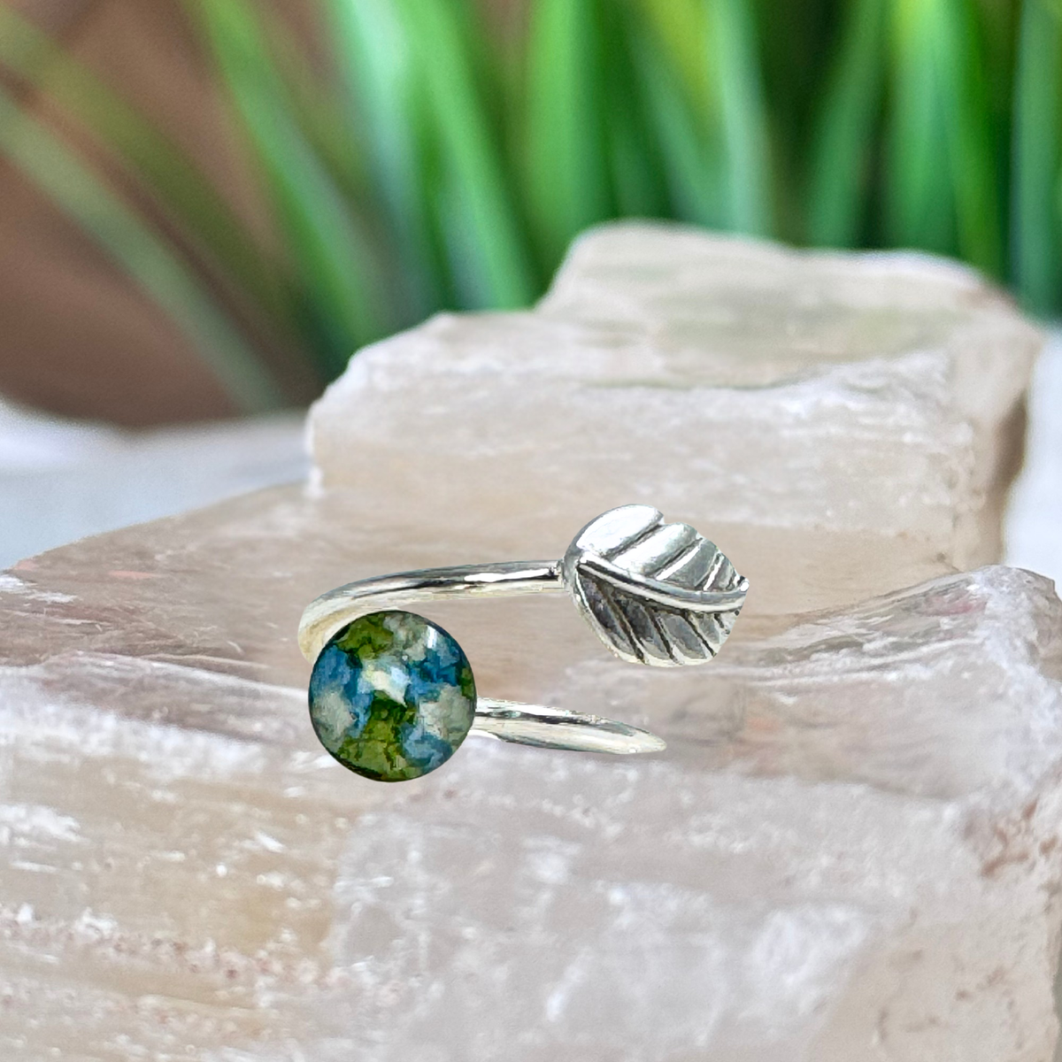 Side view of the Everleaf Keepsake Ring in sterling silver featuring an 8mm keepsake setting with preserved blue, green, and white flower petals. A handcrafted flower preservation ring made from wedding flowers, funeral flowers, cremation ashes, or pet fur.