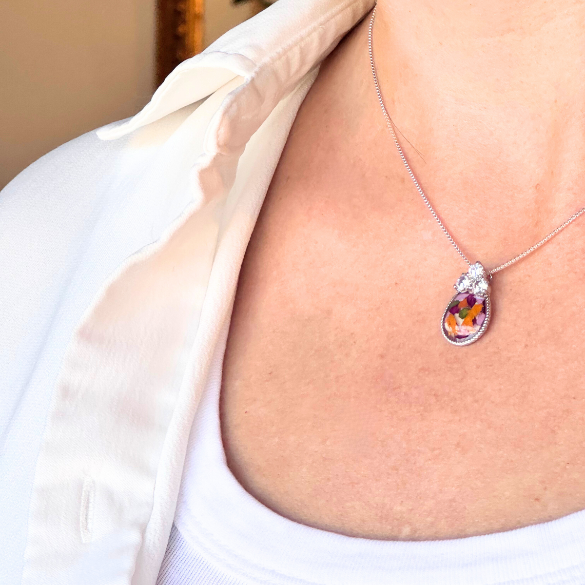 Model wearing the Forever in My Heart Pendant, a sterling silver memorial keepsake made with preserved flowers
