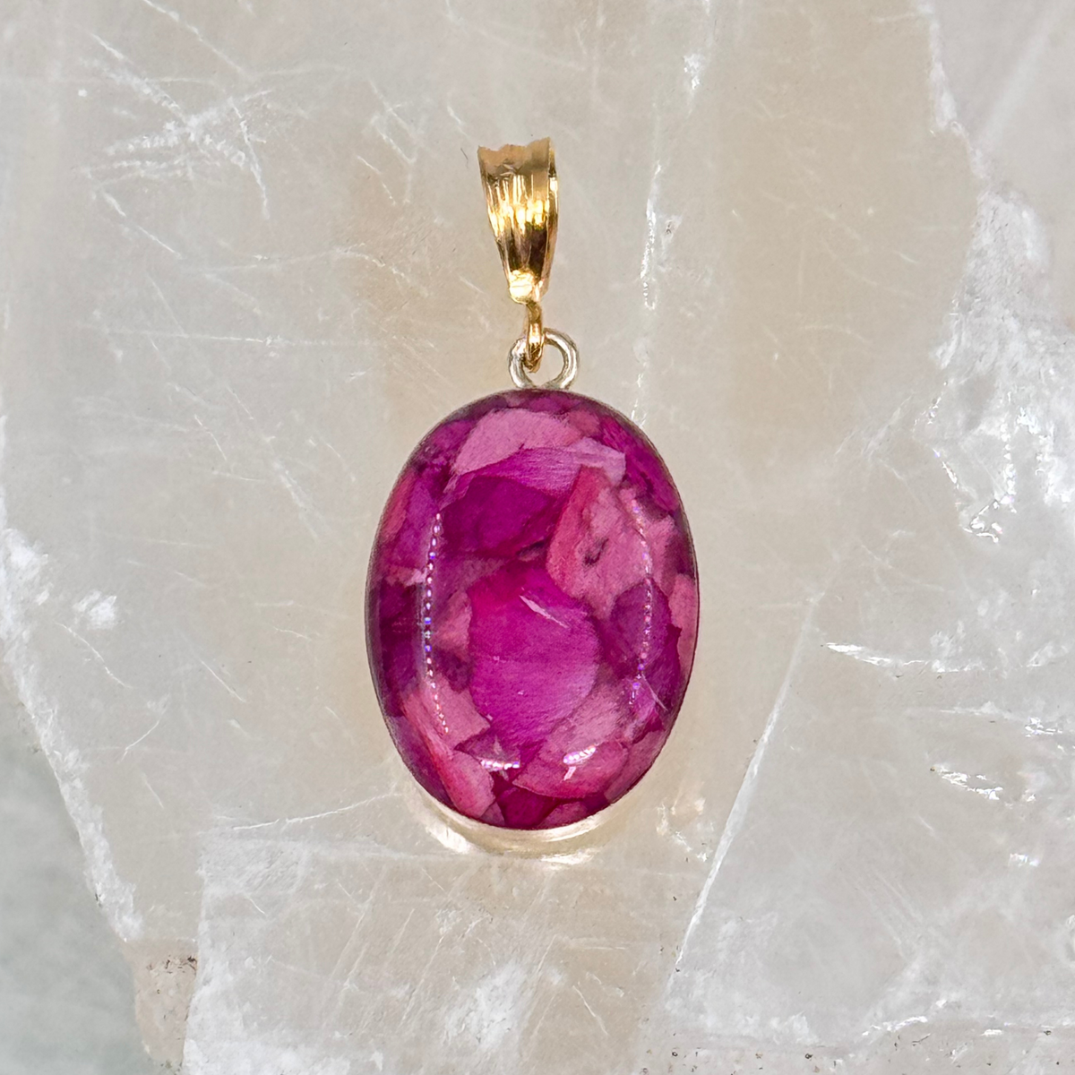A gold-filled oval memorial pendant featuring a handmade inlay with preserved pink flowers, creating a timeless tribute.