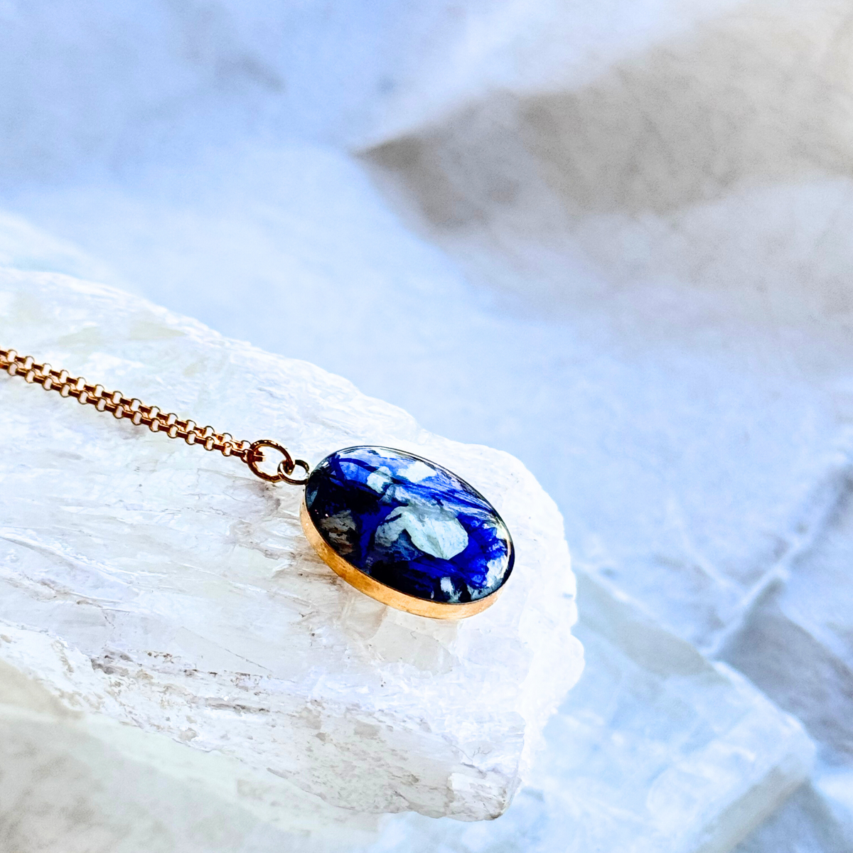 A side view of the Gold Timeless Floral Keepsake pendant, showcasing its gold-filled setting and blue and white floral inlay.