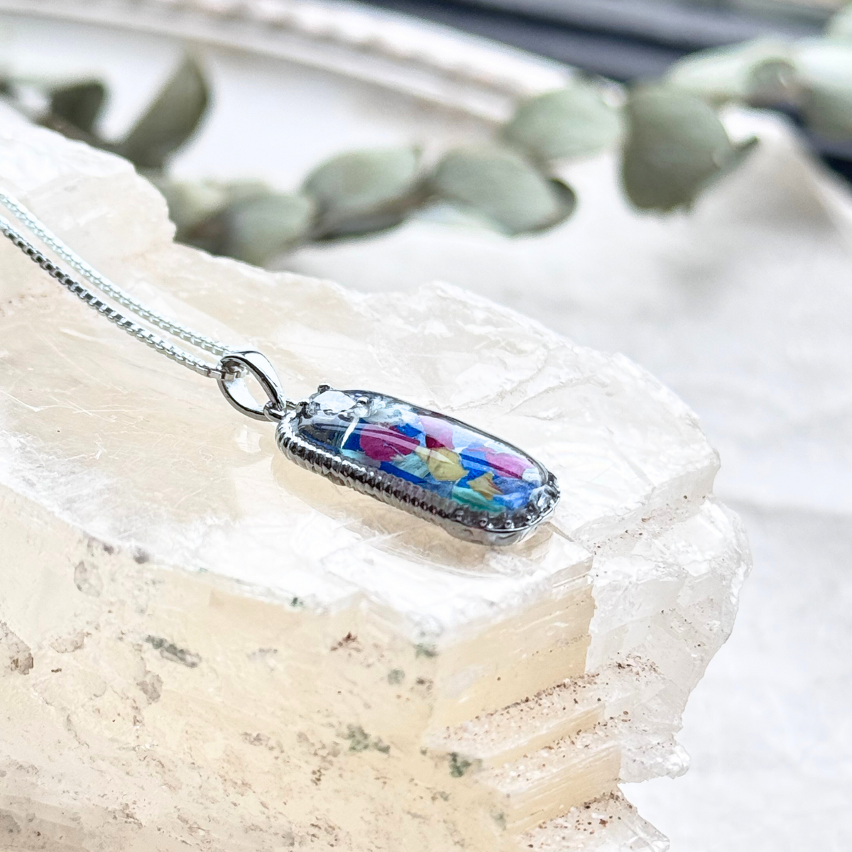 Side view of the Graceful Remembrance Pendant showcasing preserved flowers and sterling silver craftsmanship with a CZ accent.