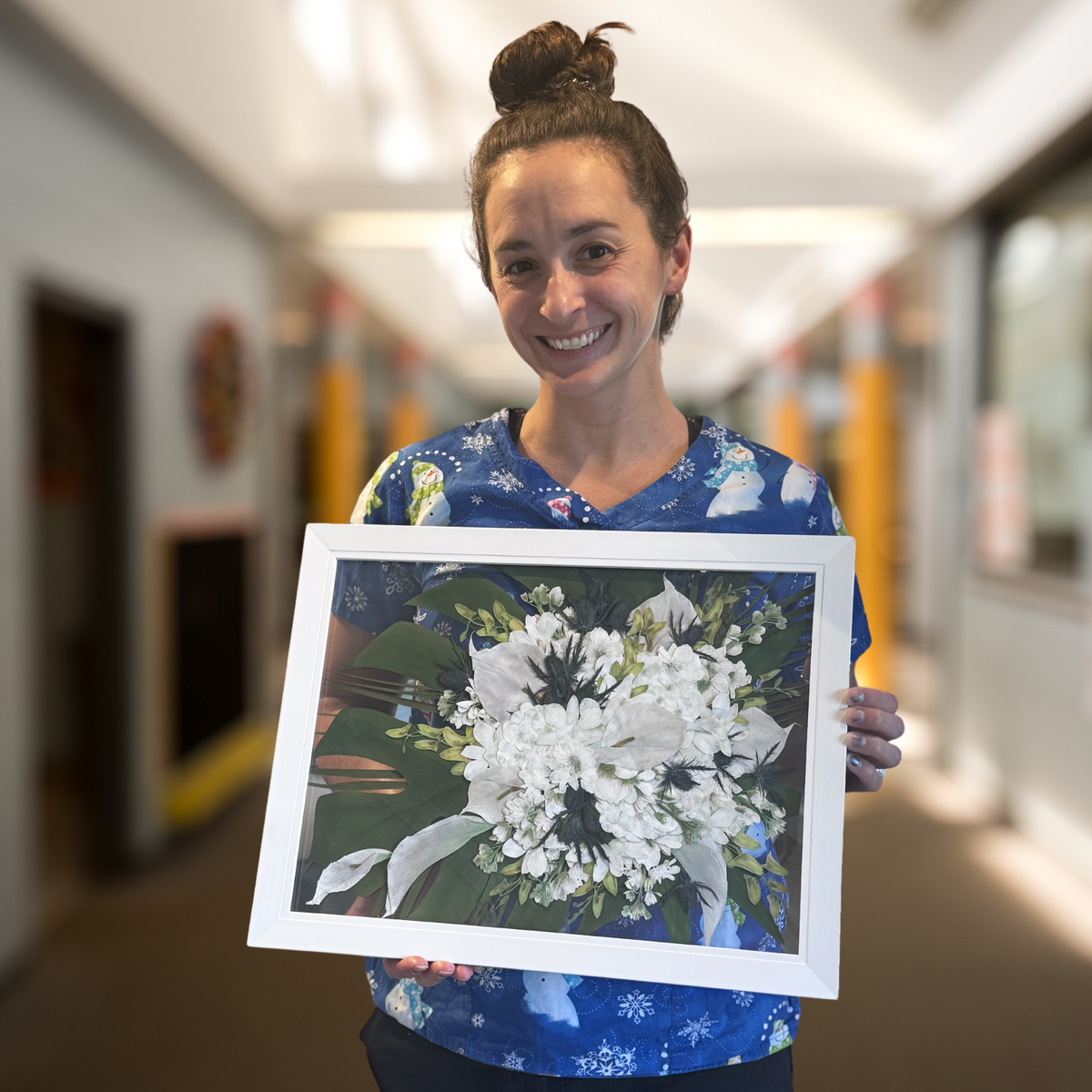 A joyful bride holding her 16x20 pressed flower design, preserved from her wedding bouquet.