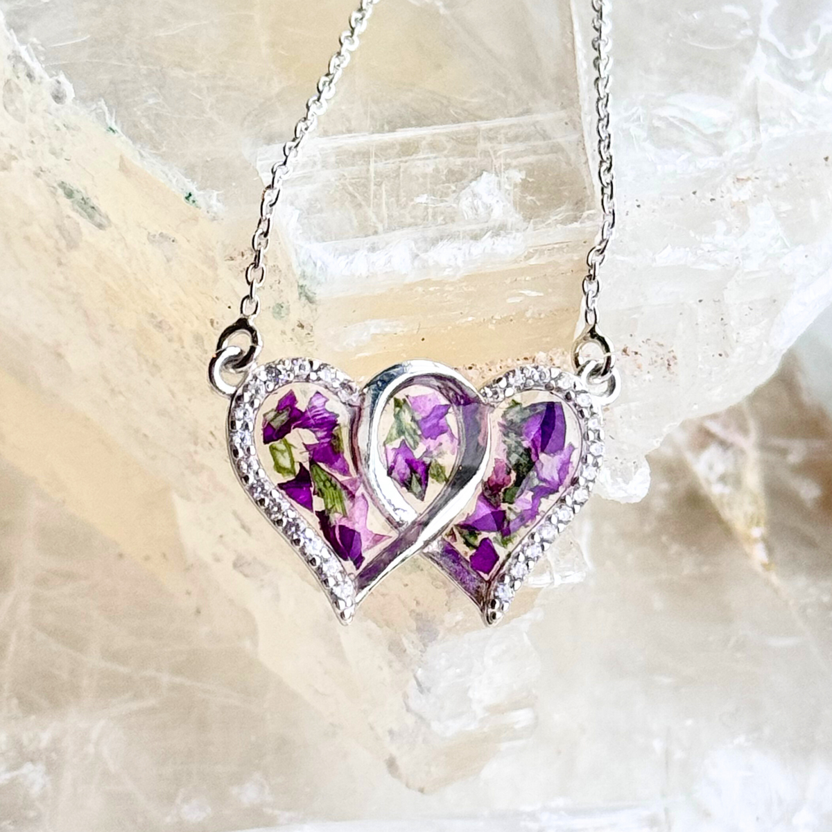 Close-up of the Infinity Heart Pendant showcasing preserved flowers and intricate sterling silver details.