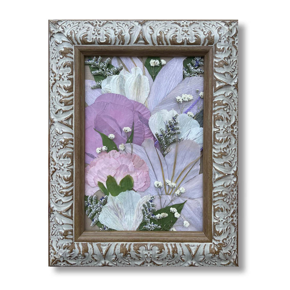 A soft and romantic 5 × 7 pressed flower arrangement featuring delicate lavender, blush pink, and ivory blooms complemented by baby&#39;s breath and soft greenery. Set in a distressed white and wood ornate frame, this keepsake captures the grace of a bridal bouquet or memorial tribute.