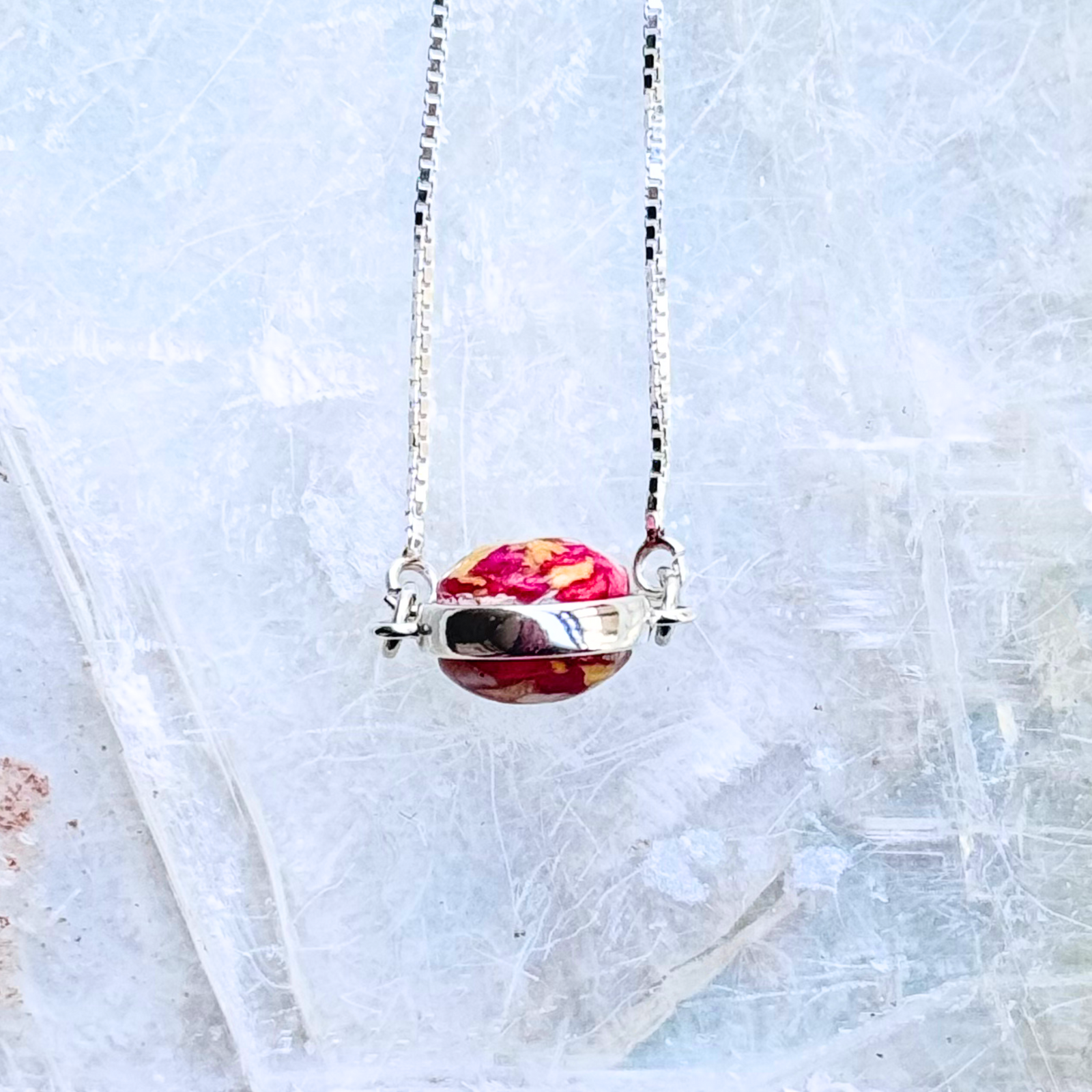  A detailed close-up of the Harmony Memorial Bracelet, featuring a double-sided bead infused with preserved funeral flowers. Set on an adjustable sterling silver chain, this handcrafted memorial jewelry piece is a beautiful tribute to cherished memories.