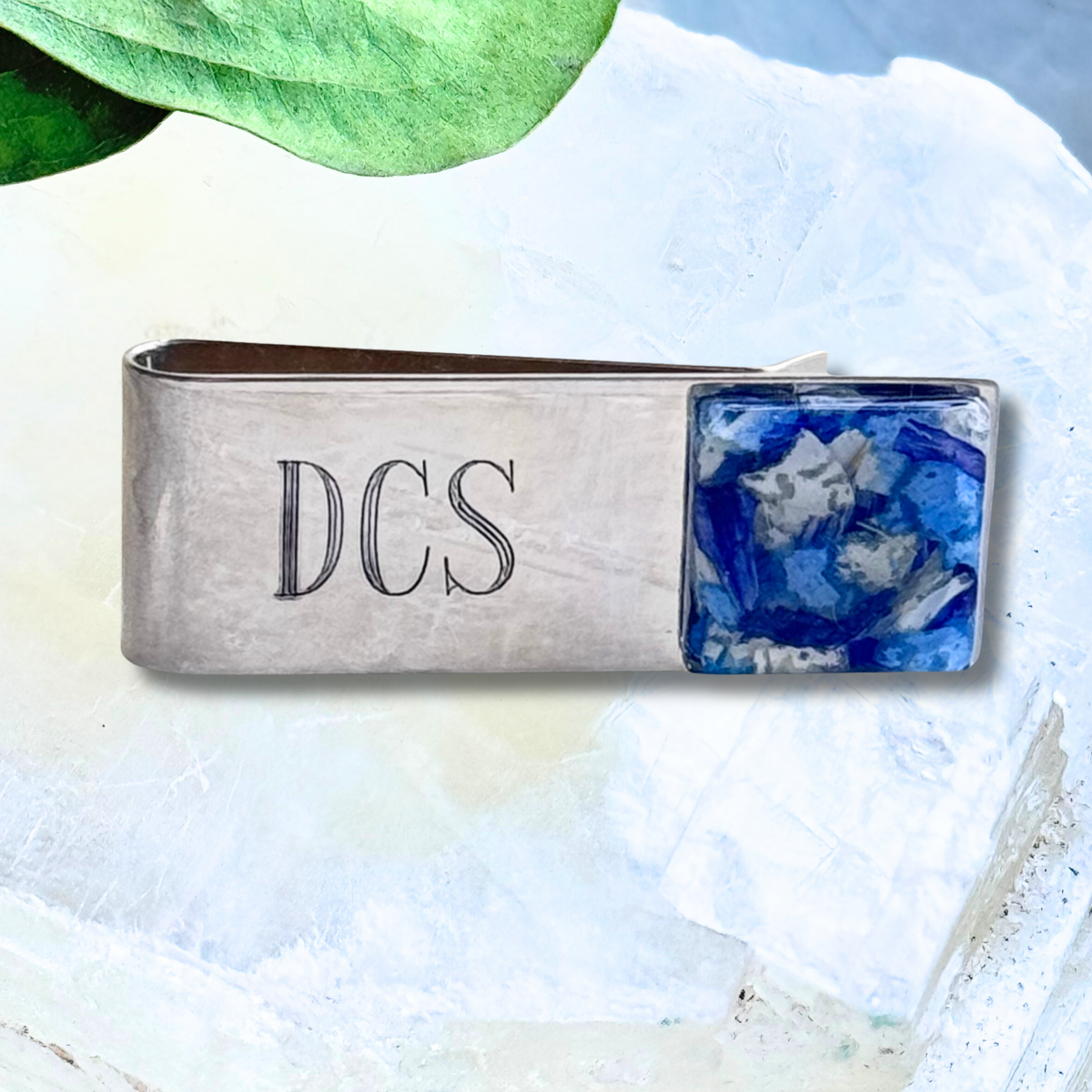 A sterling silver memorial money clip featuring a custom floral inlay with preserved funeral flowers and engraved initials.