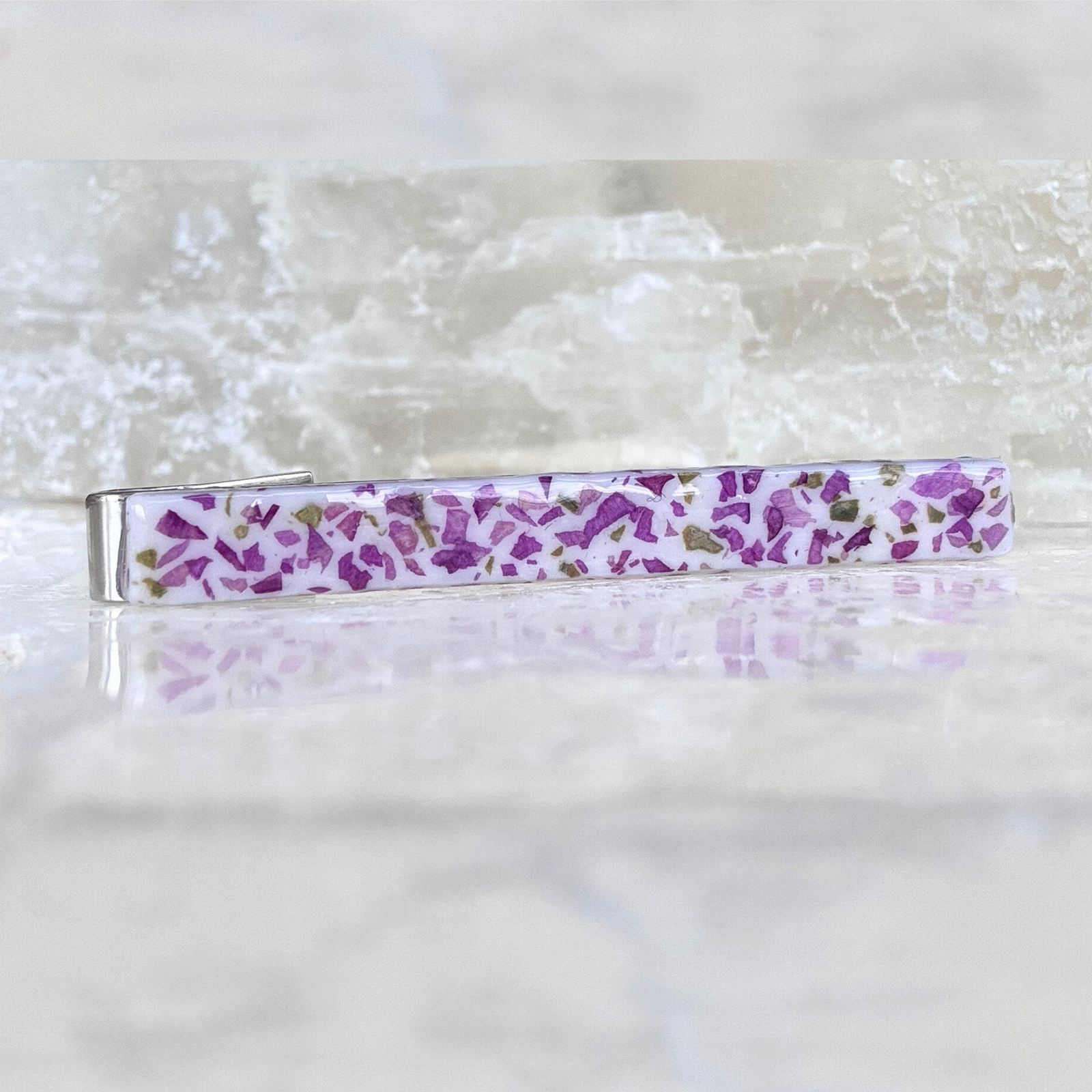 A sterling silver memorial tie bar with a handmade inlay made with preserved funeral flowers, creating a timeless tribute.
