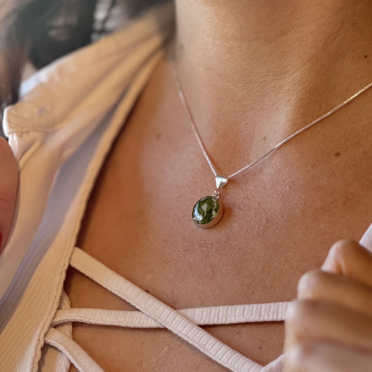 Model wearing the Timeless Blossom Pendant, featuring preserved flowers in a sterling silver setting.