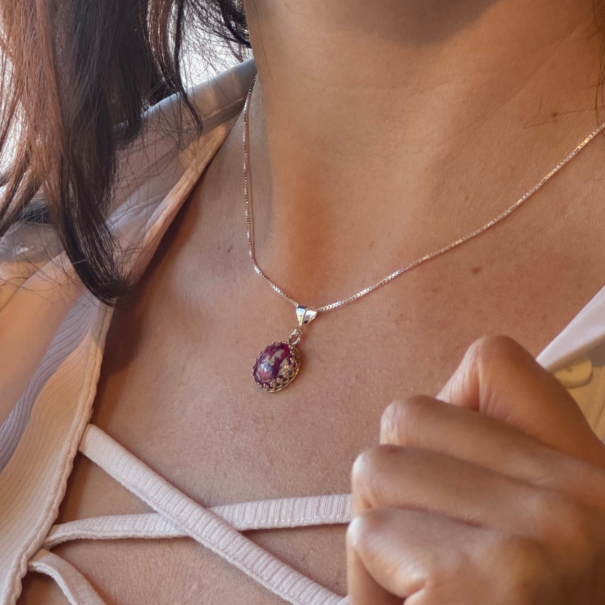 Model wearing a round sterling silver pendant and matching ring, both featuring preserved flowers.