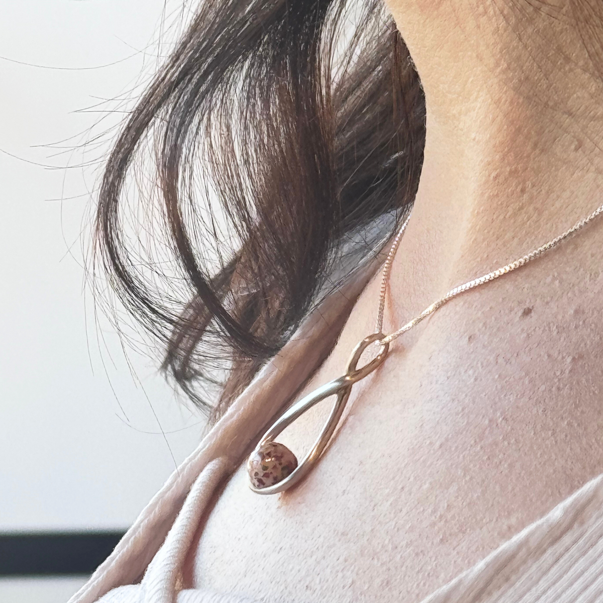 Angled side view of the Serenity Bloom Pendant highlighting the preserved flowers and the flowing sterling silver design.