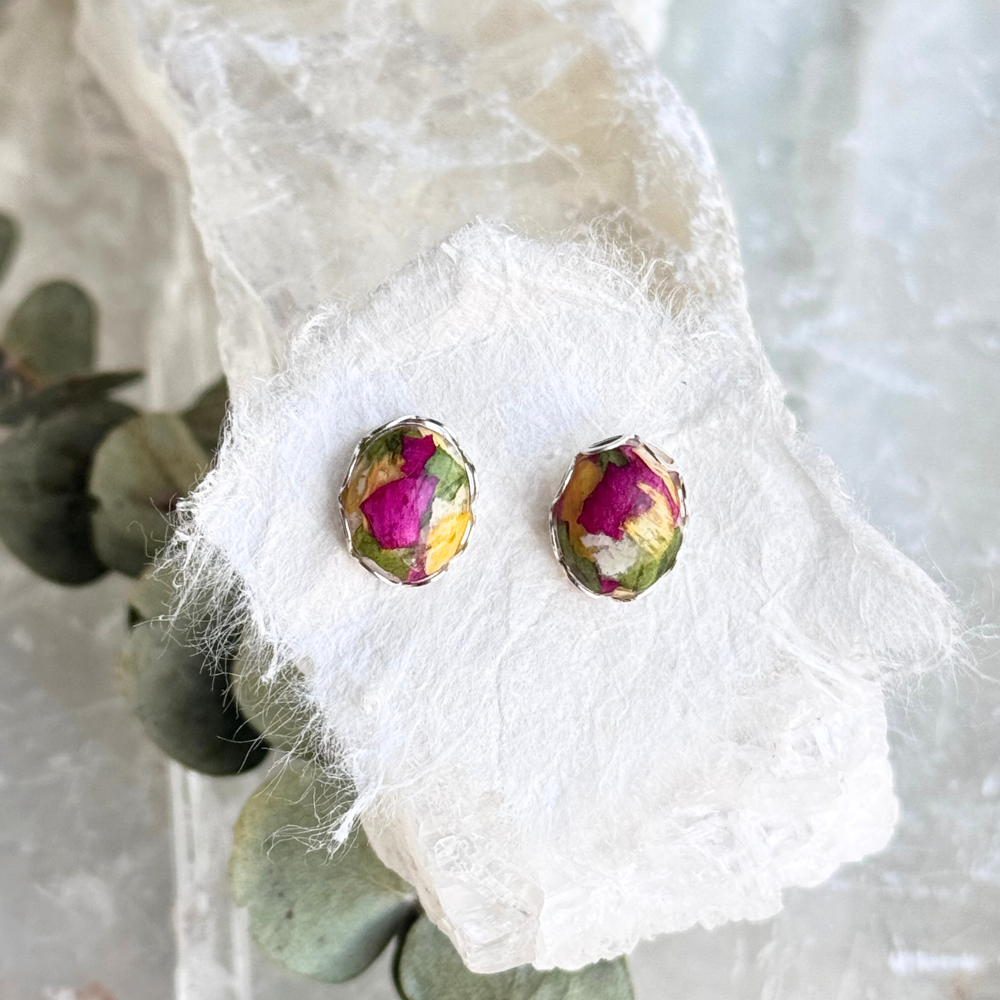 Handcrafted silver oval earrings made with preserved funeral flowers, a meaningful memorial keepsake.