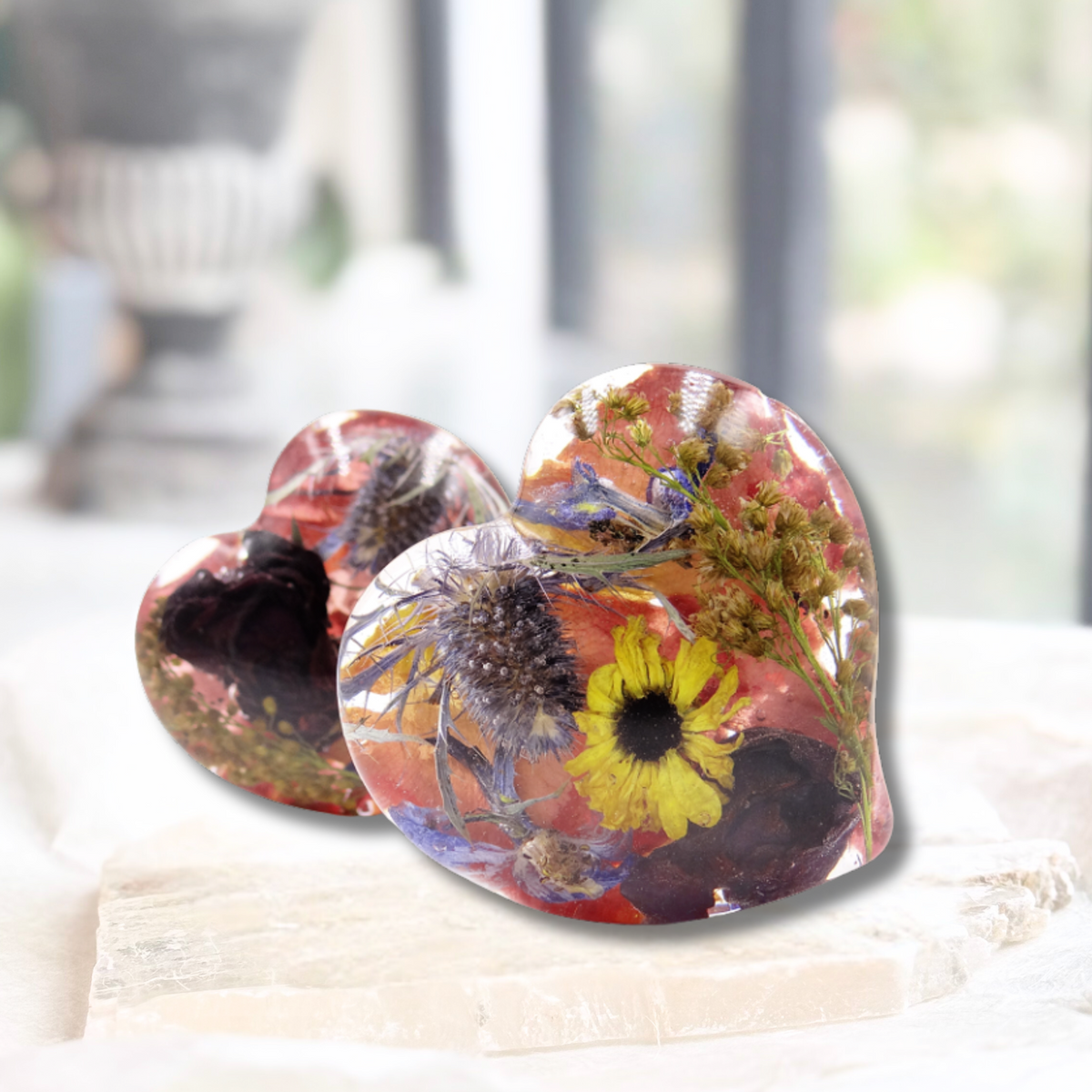Two resin hearts encased with a mix of preserved flowers and greenery.