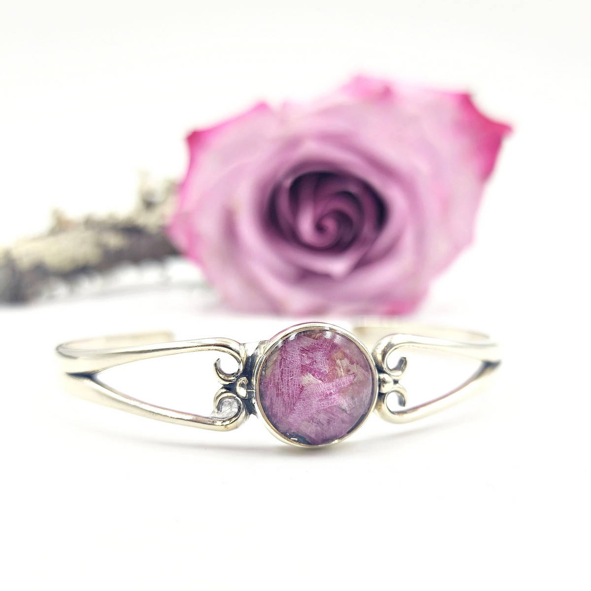 A sterling silver Unity Memorial Bracelet displayed in front of a lavender flower used to create its floral-infused bead.
