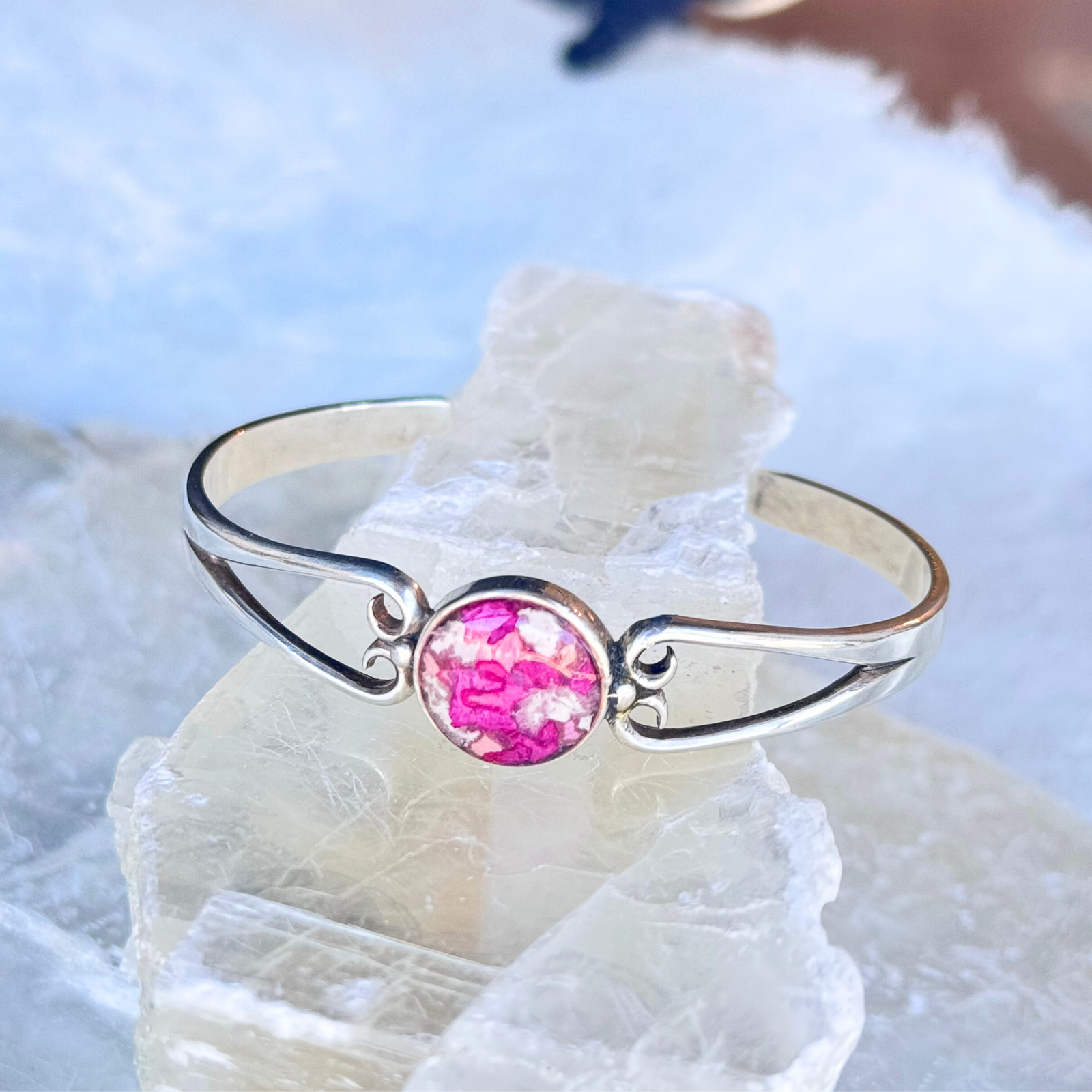 A memorial bracelet with a flower and ash-infused bead, set in sterling silver, honoring cherished memories.