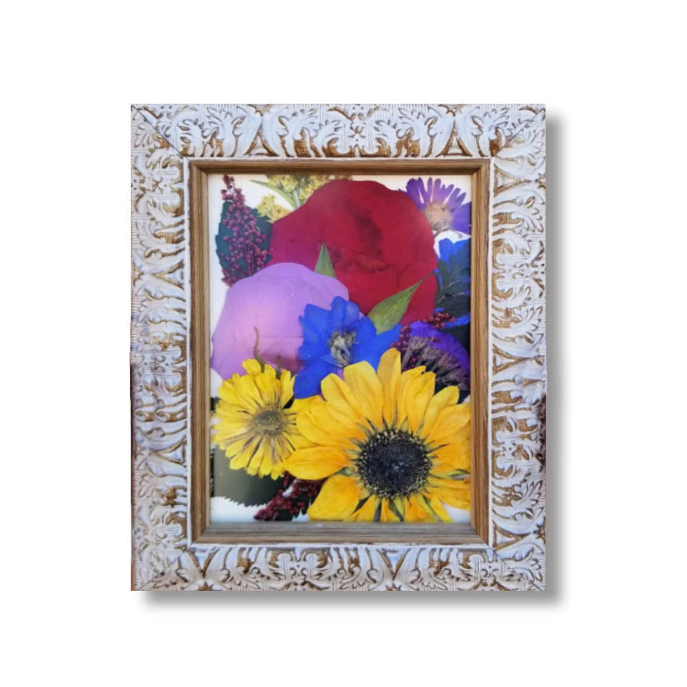 A bold and colorful 5 × 7 pressed flower arrangement featuring sunflowers, red roses, purple and blue wildflowers, and soft pink accents, set in an ornate distressed white frame. This bright floral keepsake captures the joyful essence of a wedding bouquet or the cherished memory of a loved one.
