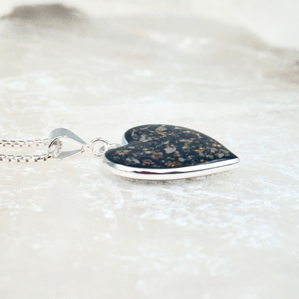 Side view of the sterling silver heart-shaped pet memorial ash pendant, showing resin depth and handcrafted detail.