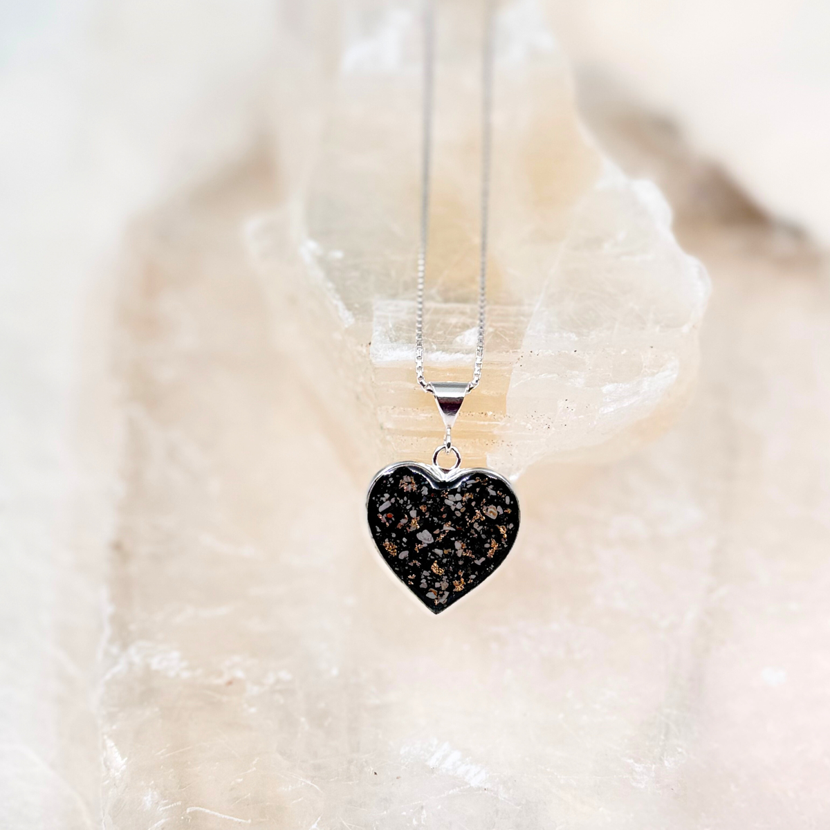 Sterling silver heart-shaped pet memorial pendant made with ashes, shown on a clean background to highlight its color and detail.