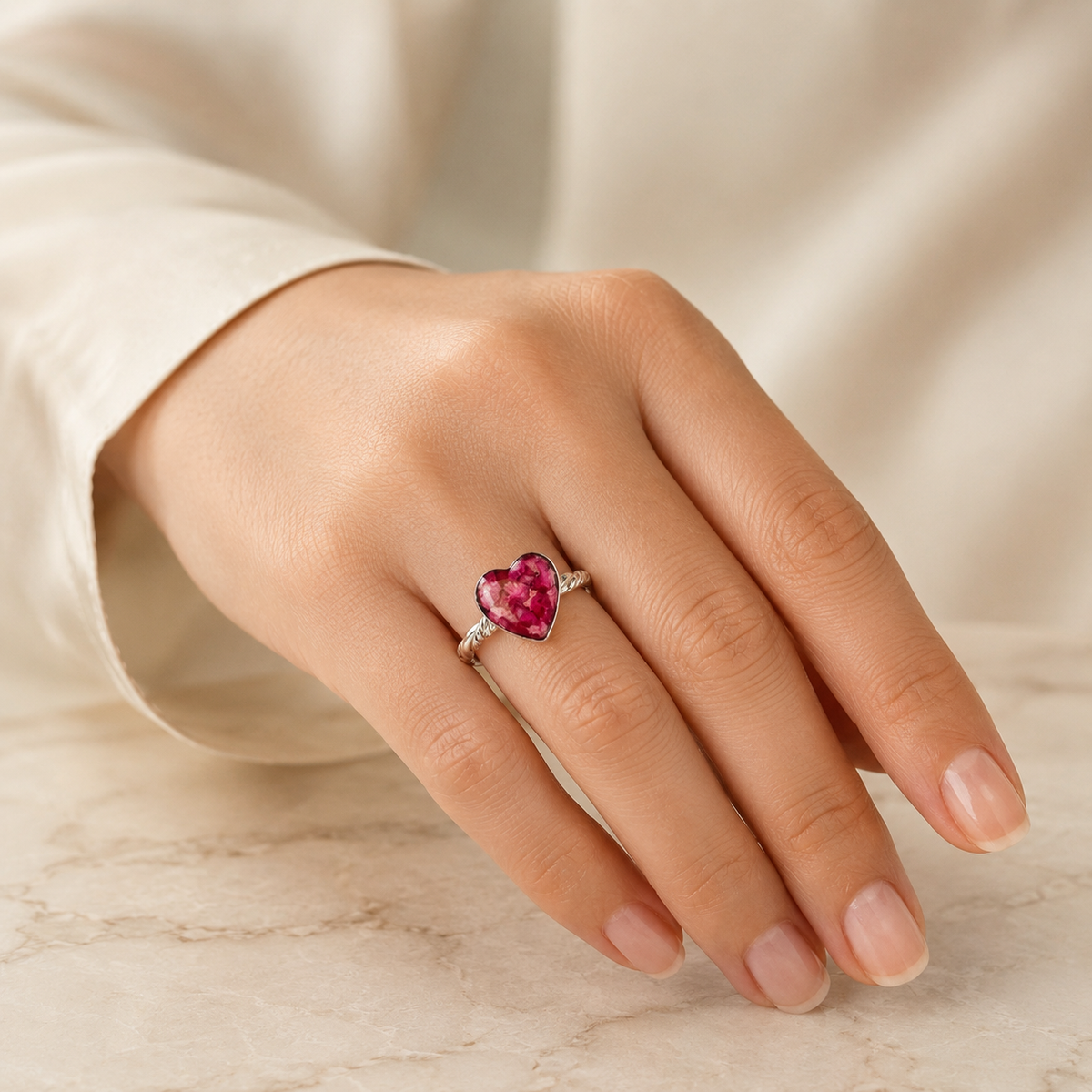 Model wearing Beloved Heart Keepsake Silver Ring with pink preserved flowers.