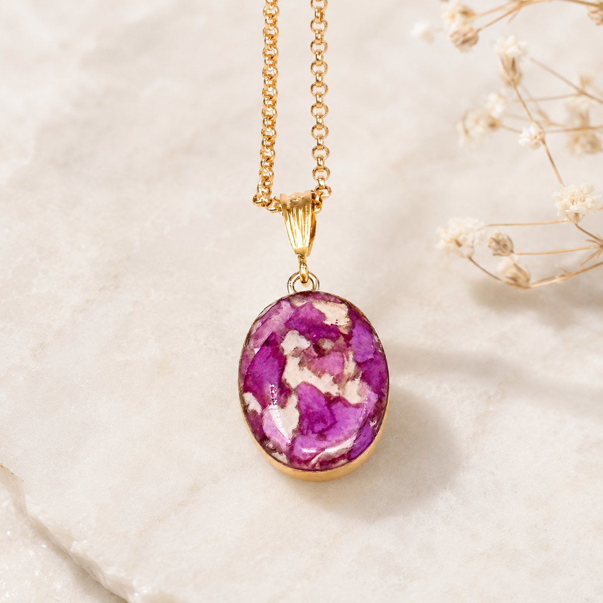 Blossom of Memories Pendant with purple and white preserved flowers in a gold setting.