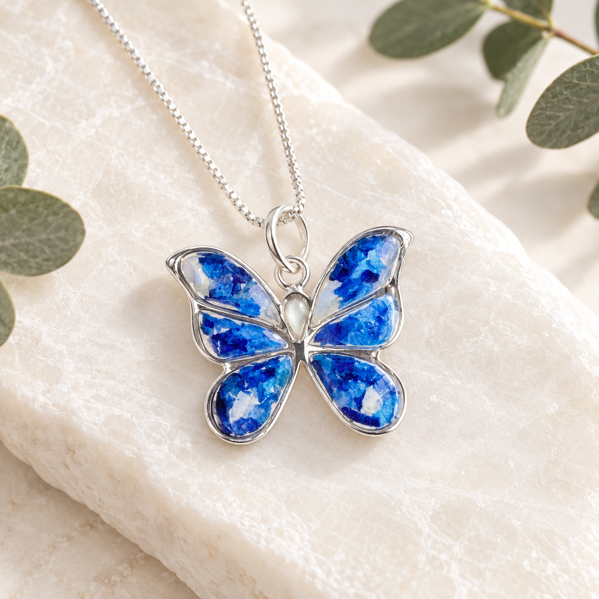 Sterling silver butterfly keepsake pendant handcrafted with blue preserved flowers.