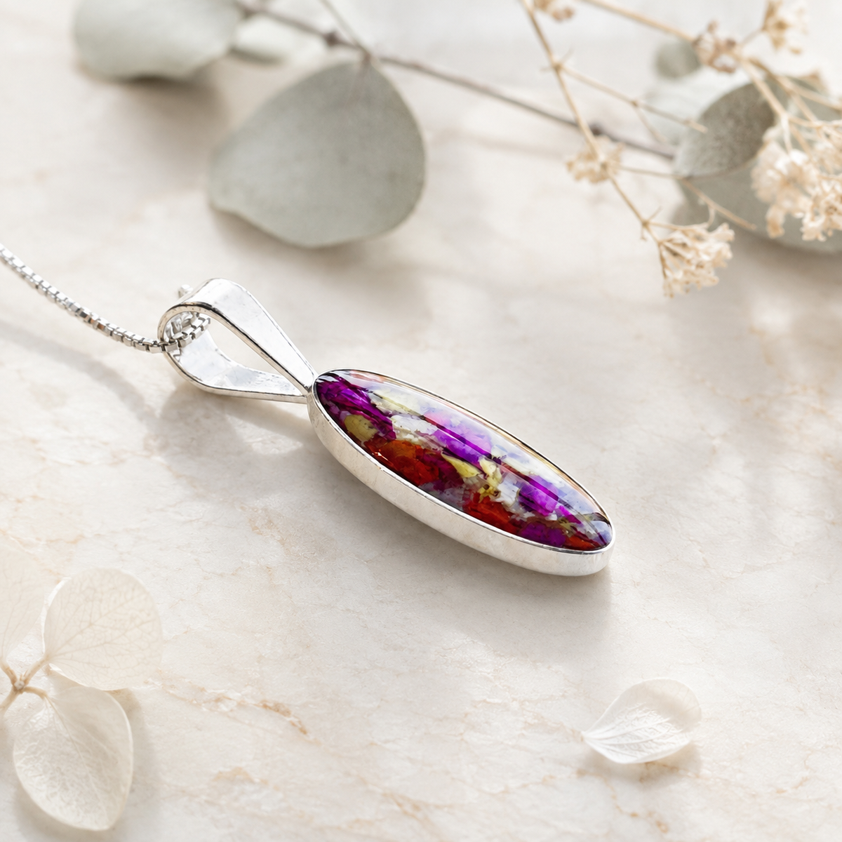Eternal Grace Pendant with colorful preserved flowers shown in a styled side view.