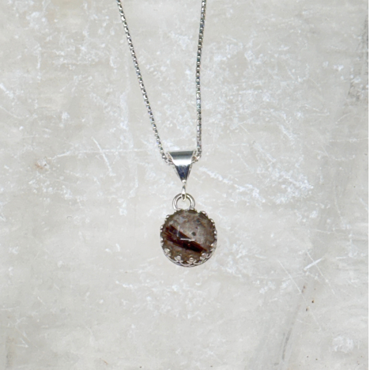 Front view of the Ever Close pet memorial pendant, highlighting the arrangement of ashes and hair within the round resin stone and sterling silver bezel.