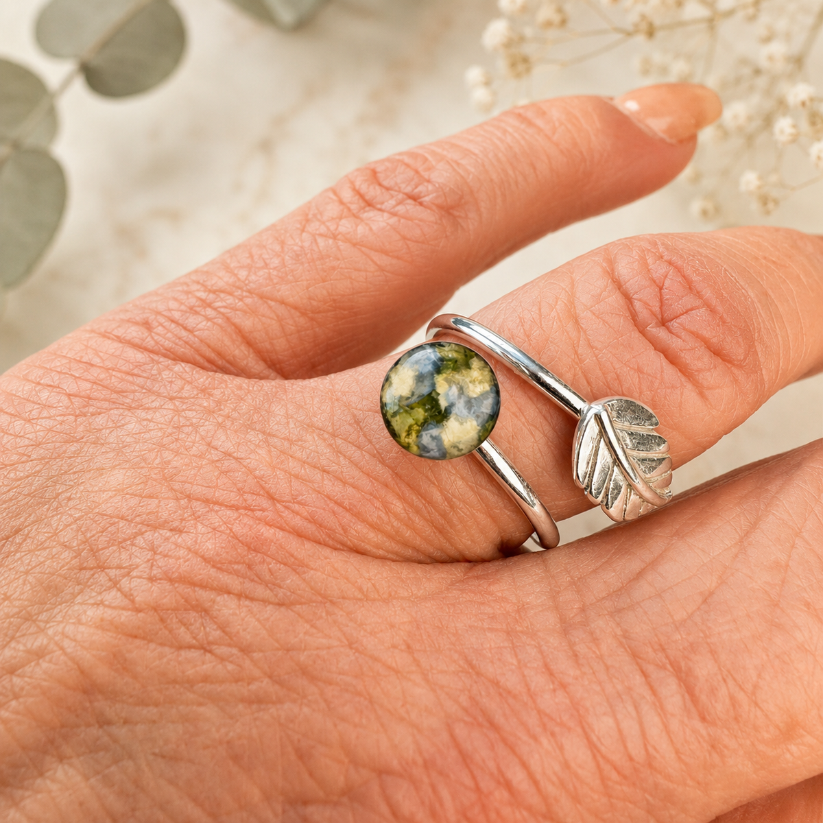 Everleaf Keepsake Ring with blue, green and white preserved flowers shown on hand.