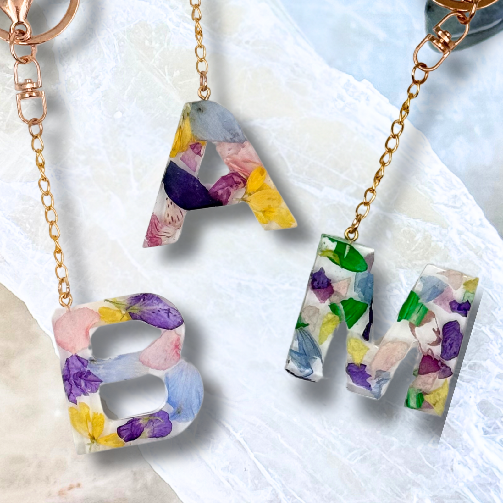 Handmade resin keychains with real flower petals in letters A, M, and B, custom keepsakes made from your own flowers