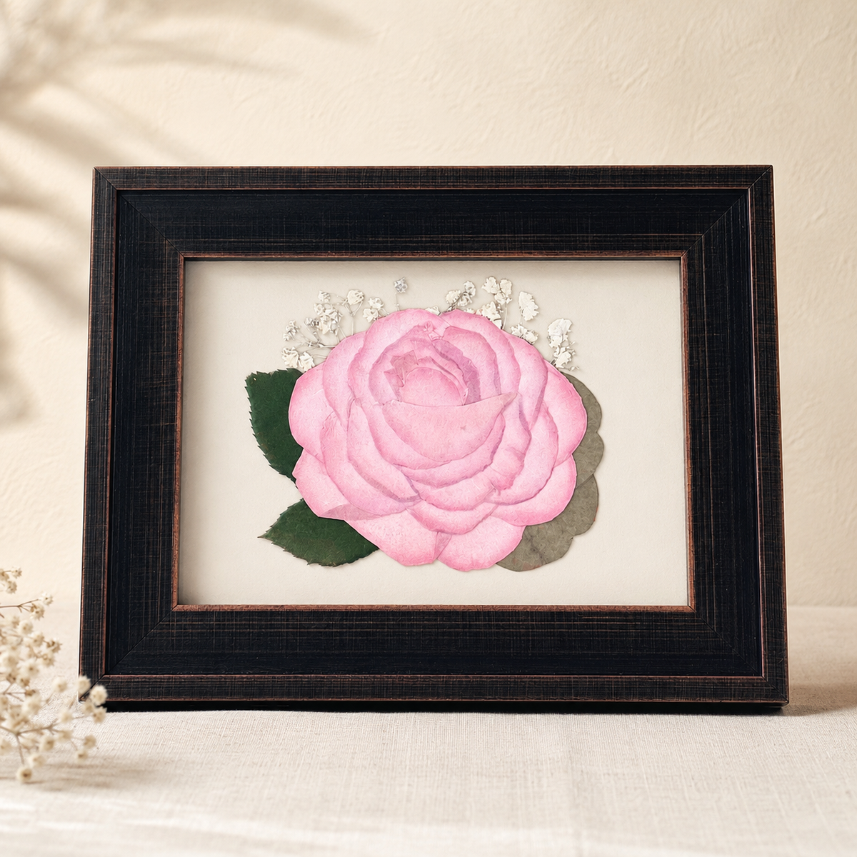 Pressed pink rose with baby’s breath and greenery preserved in a 5x7 frame.