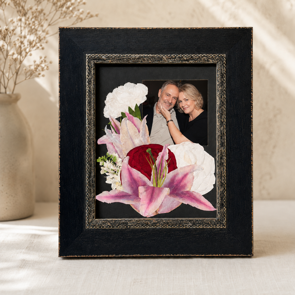 Pressed pink, red and white flowers arranged with a photo in a black 8x10 frame.