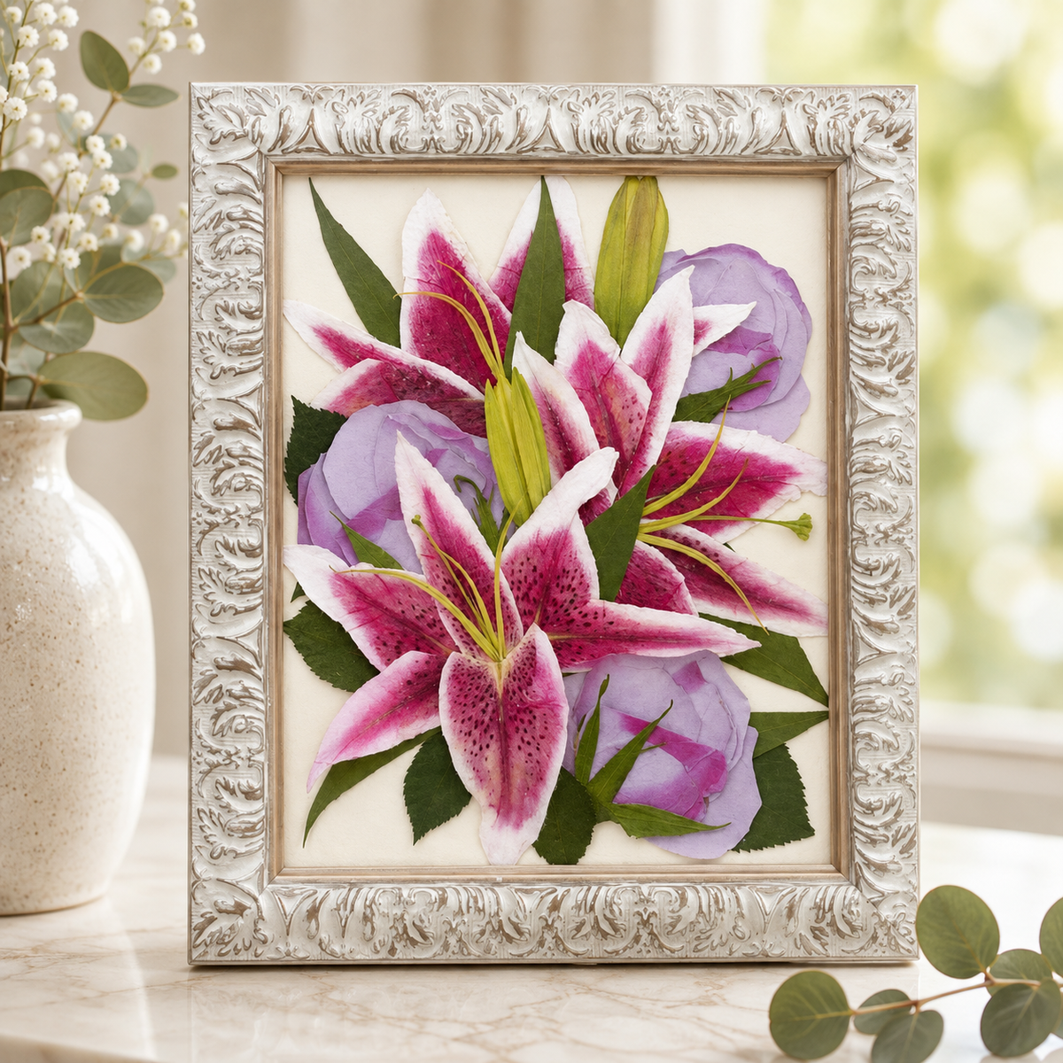 Pressed pink lilies and lavender roses with greenery preserved in an ornate white 8x10 frame.