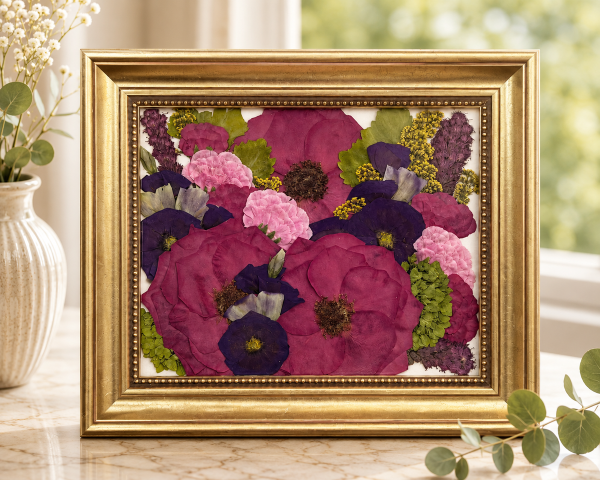 Pressed pink, purple and green flowers preserved in an ornate gold 8x10 frame.