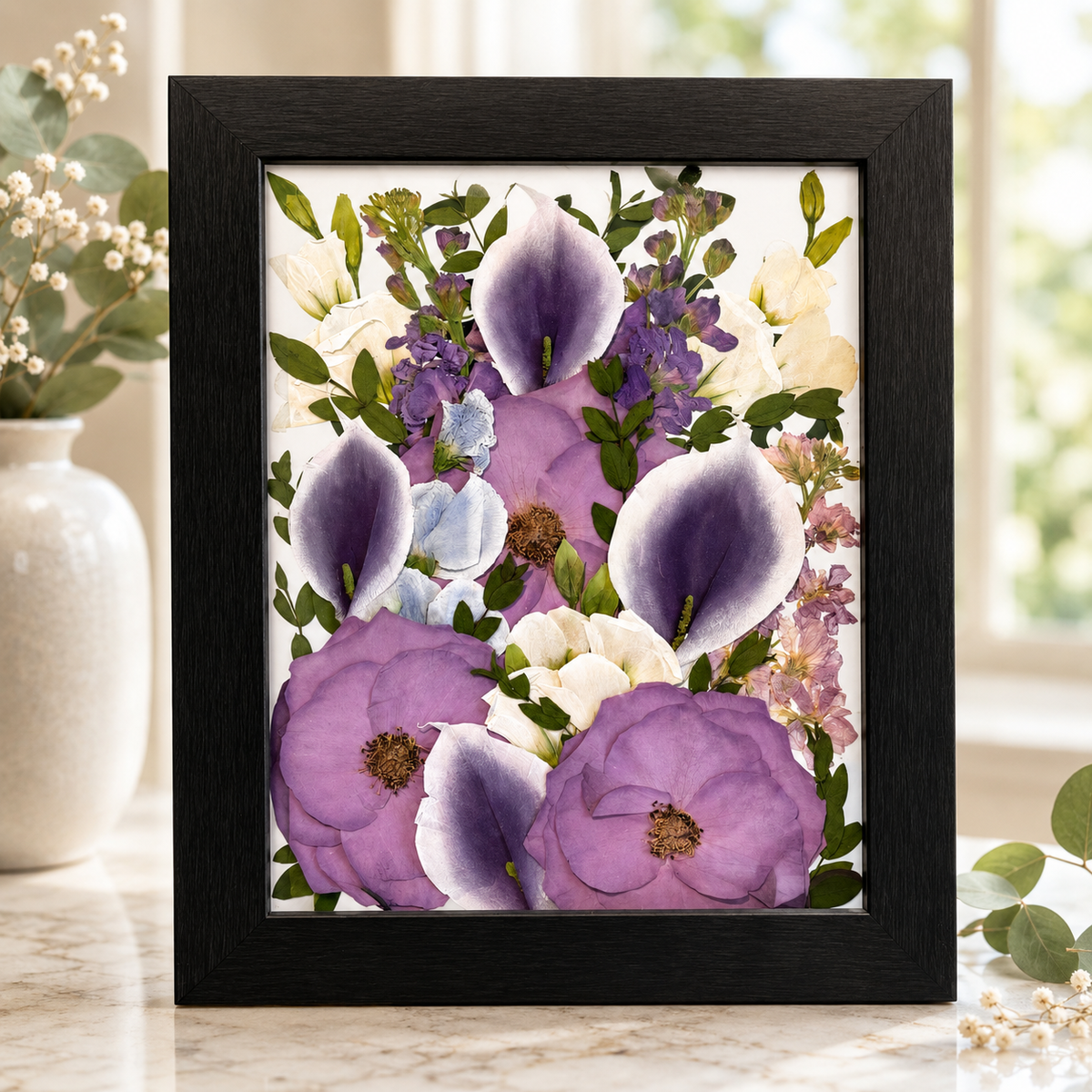 Pressed purple and white flowers with greenery preserved in a black 8x10 frame.