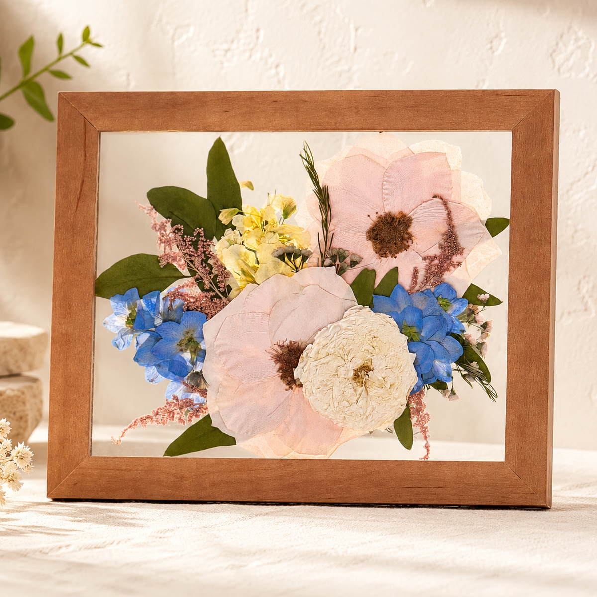 Pressed white and blue flowers with greenery preserved in a light wood 8x10 frame.