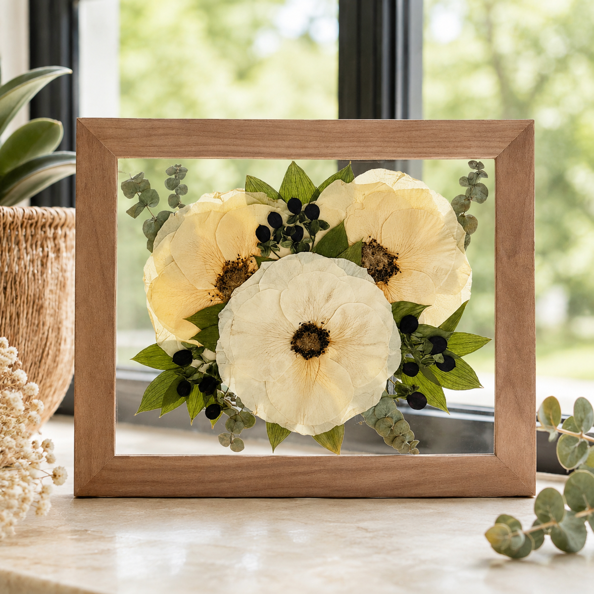 Pressed white flowers with greenery and dark berries preserved in a wood 8x10 frame.
