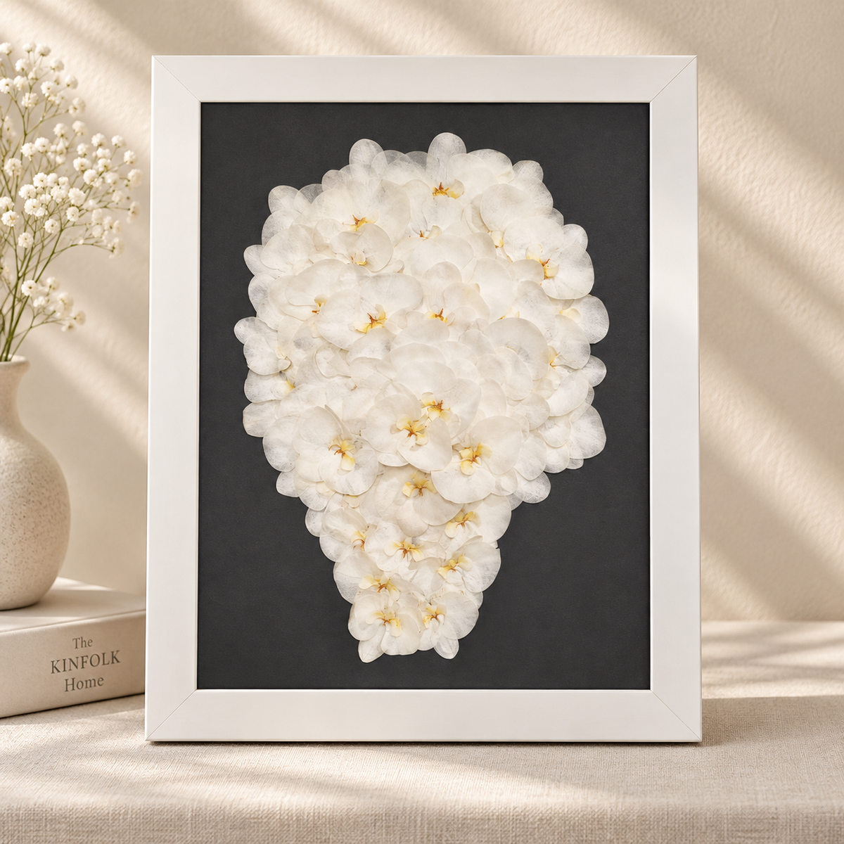Pressed white orchids arranged on a black background and preserved in a white frame.