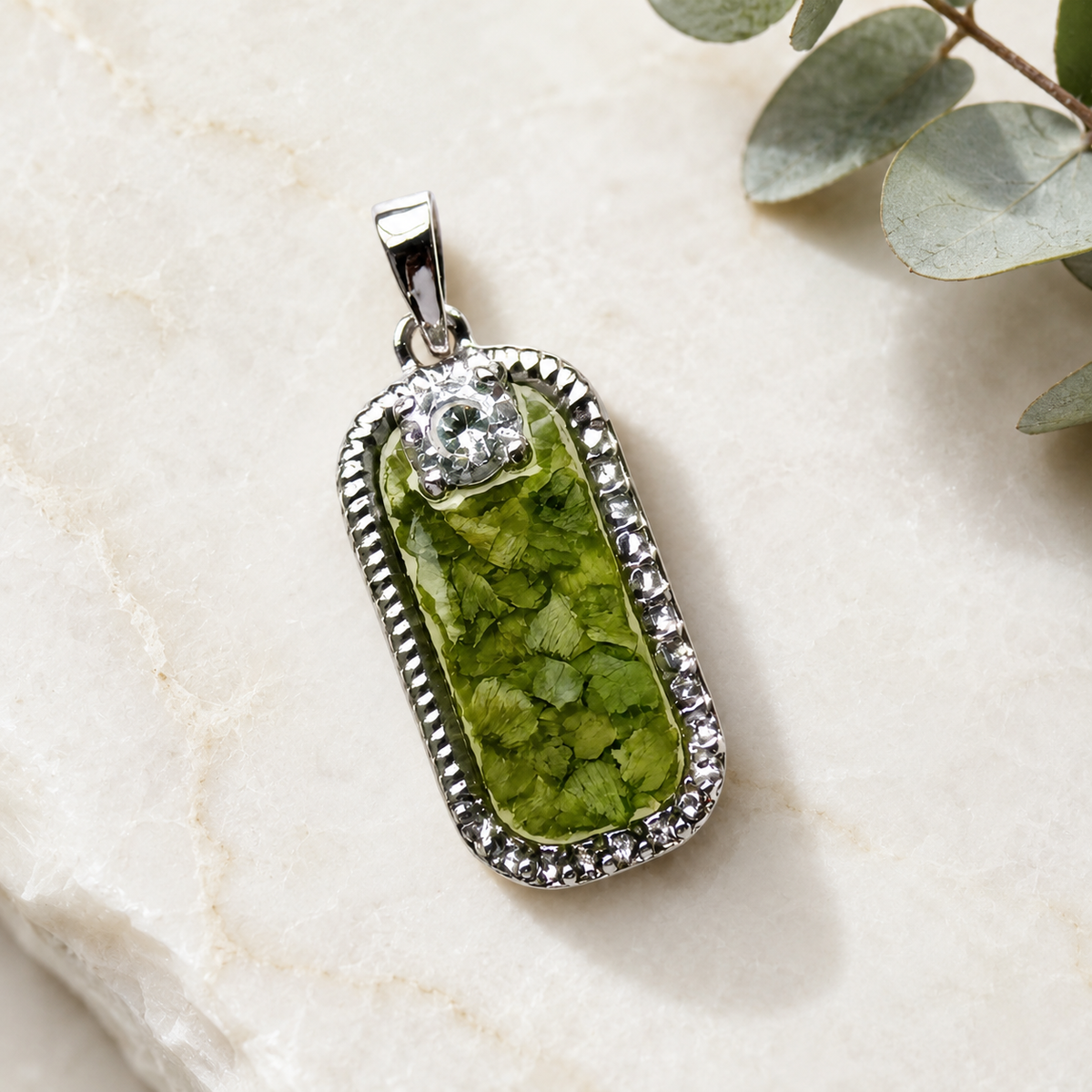 Graceful Remembrance Pendant with green preserved flowers in a silver setting.