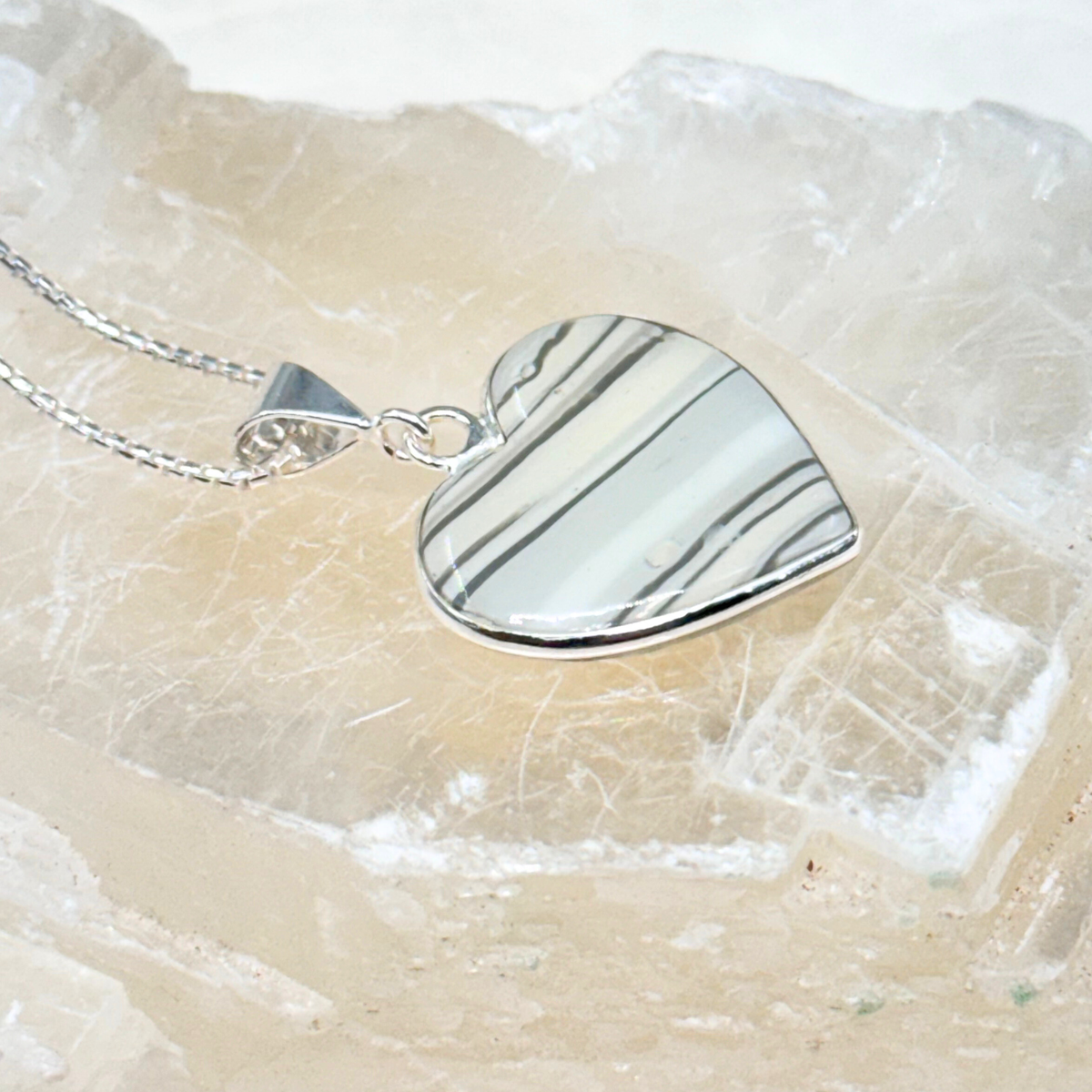 Side view of the Heart Pet Memorial Pendant made with cat ashes or fur, showing the depth of the resin and sterling silver setting.