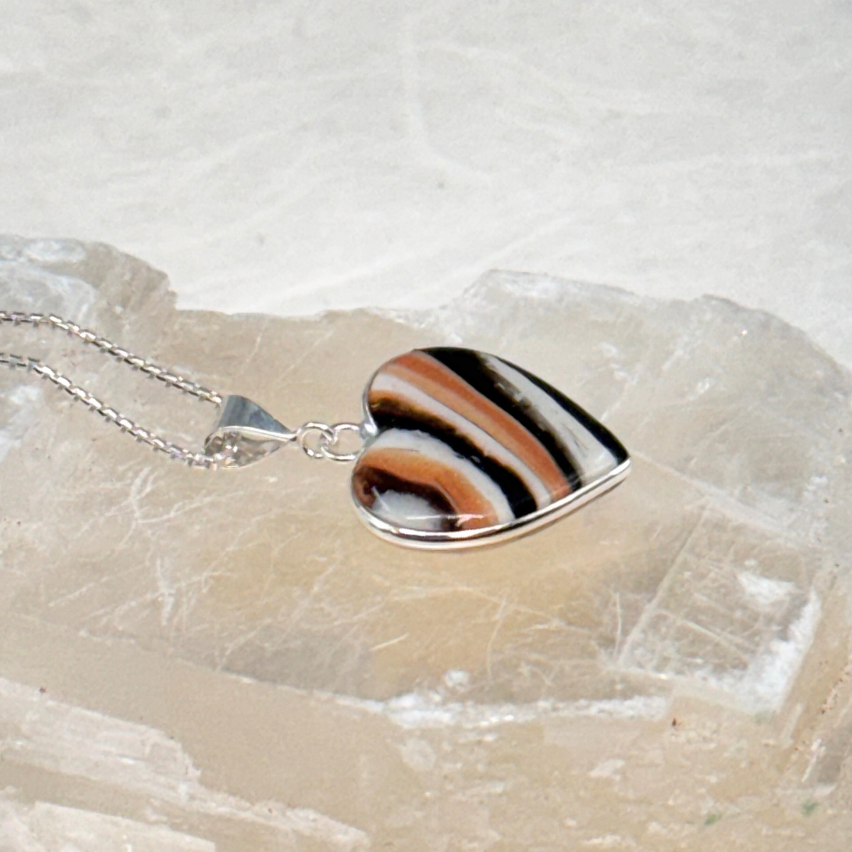 Side view of the Heart Pet Memorial Pendant, showing the depth of the resin and sterling silver heart-shaped setting crafted with ashes or fur.